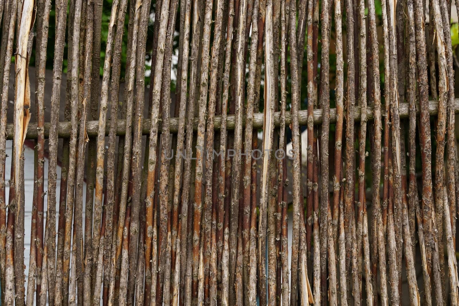 Brown texture of a fence made of thin willow branches. Close-up.