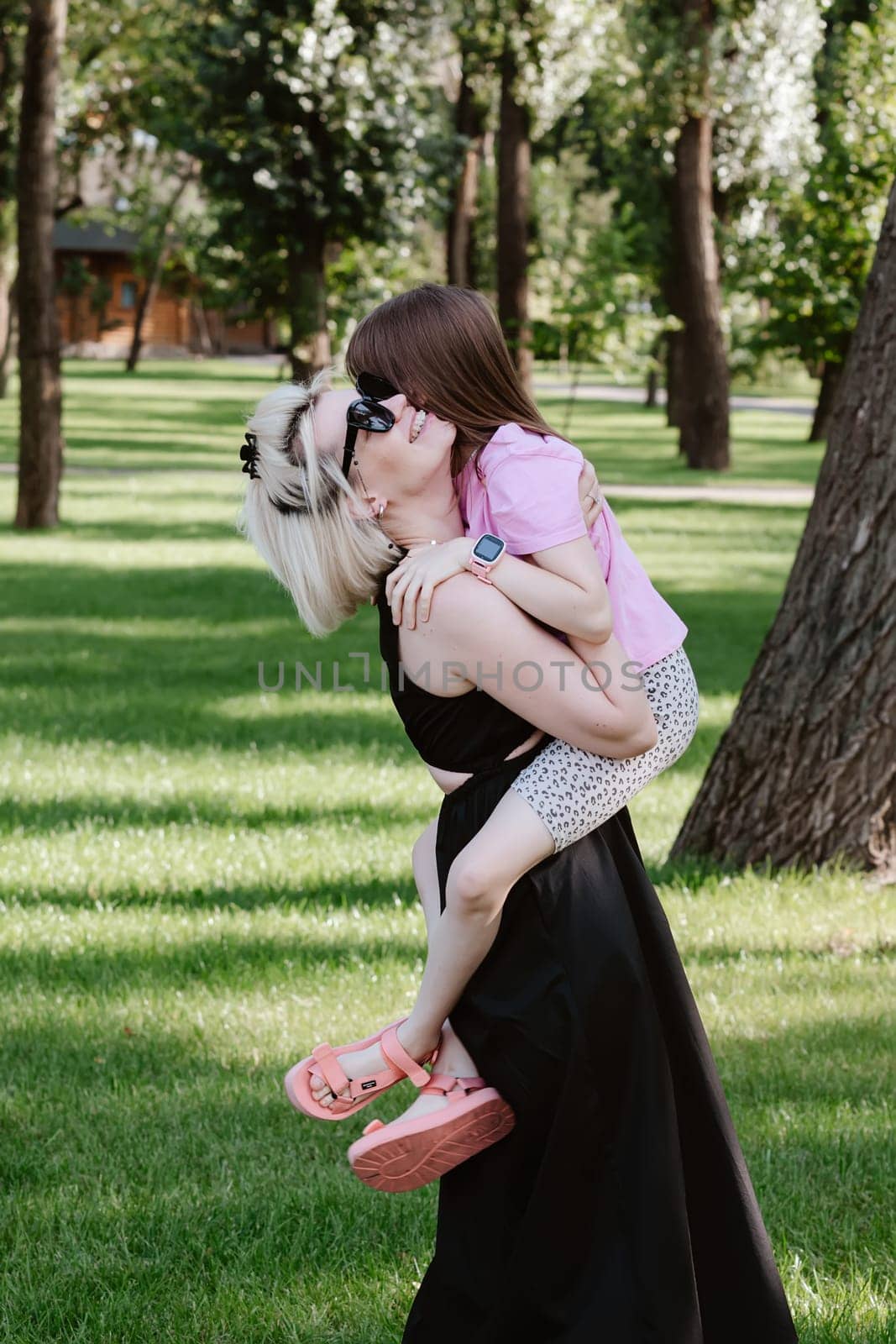 Girl hugging mother in spring or summer park. Family relaxing outdoors. Mothers day. Close up by sarymsakov
