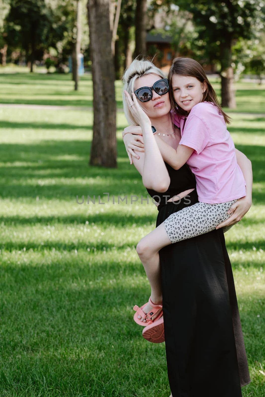 Girl hugging mother in spring or summer park. Family relaxing outdoors. Mothers day. Close up.