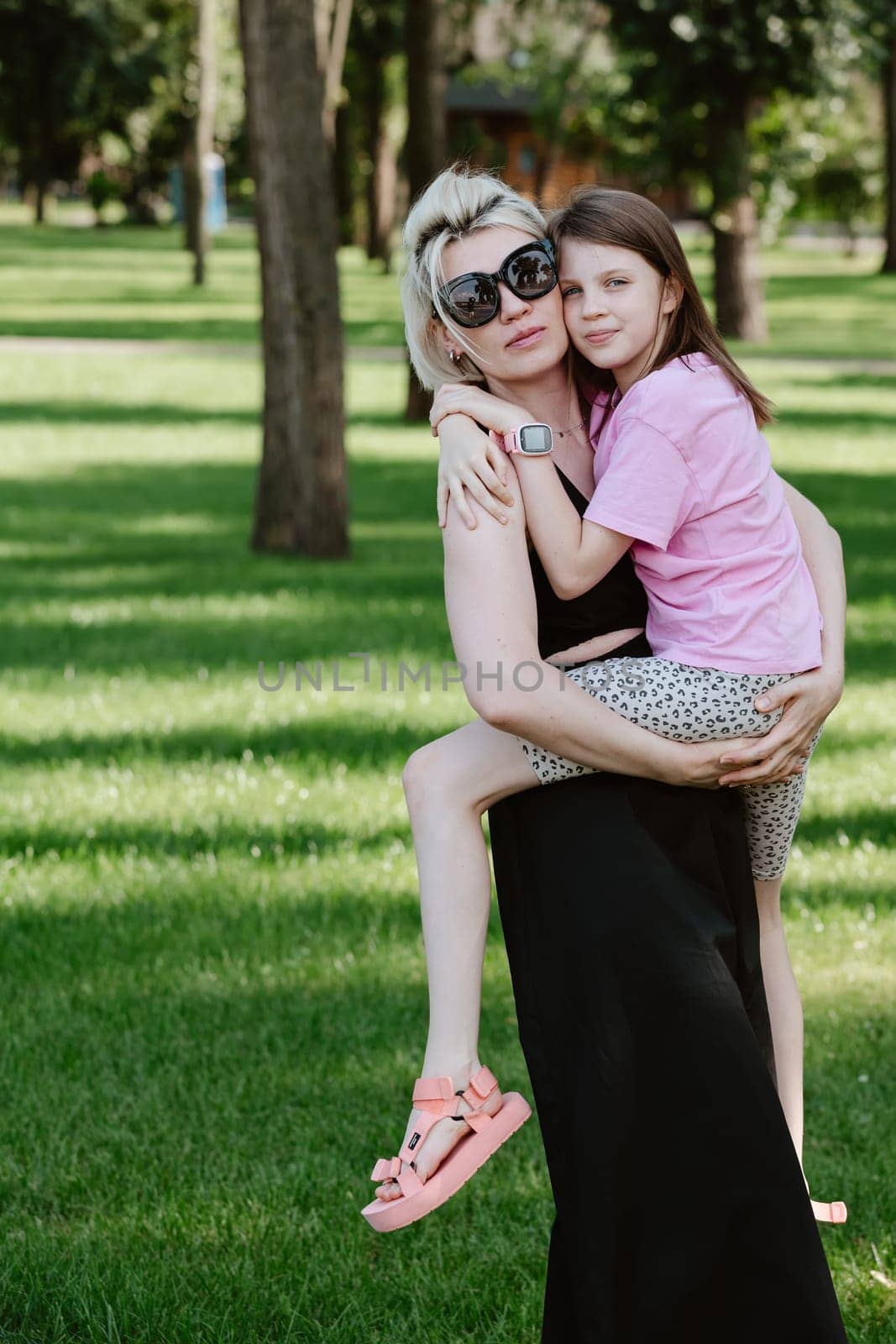 Girl hugging mother in spring or summer park. Family relaxing outdoors. Mothers day. Close up by sarymsakov