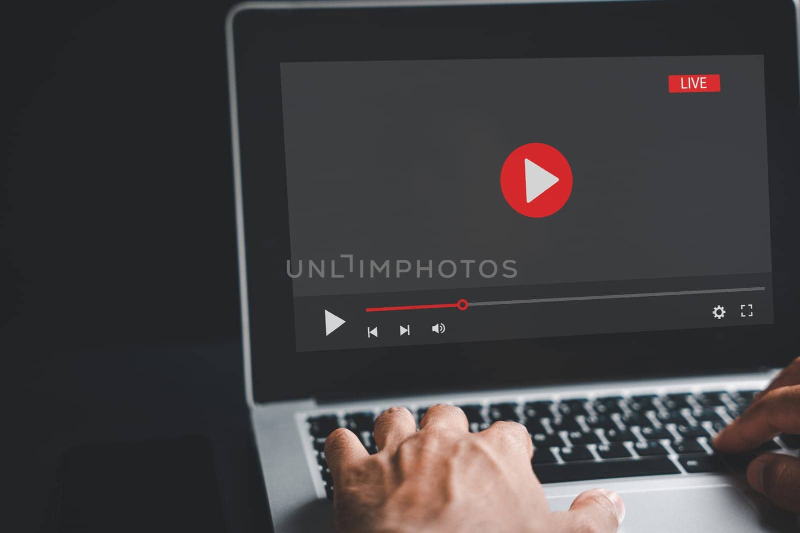 A man engrossed in his laptop screen, seamlessly switching between a video player and online training, embodying the concept of telework and e-learning from the comfort of home.