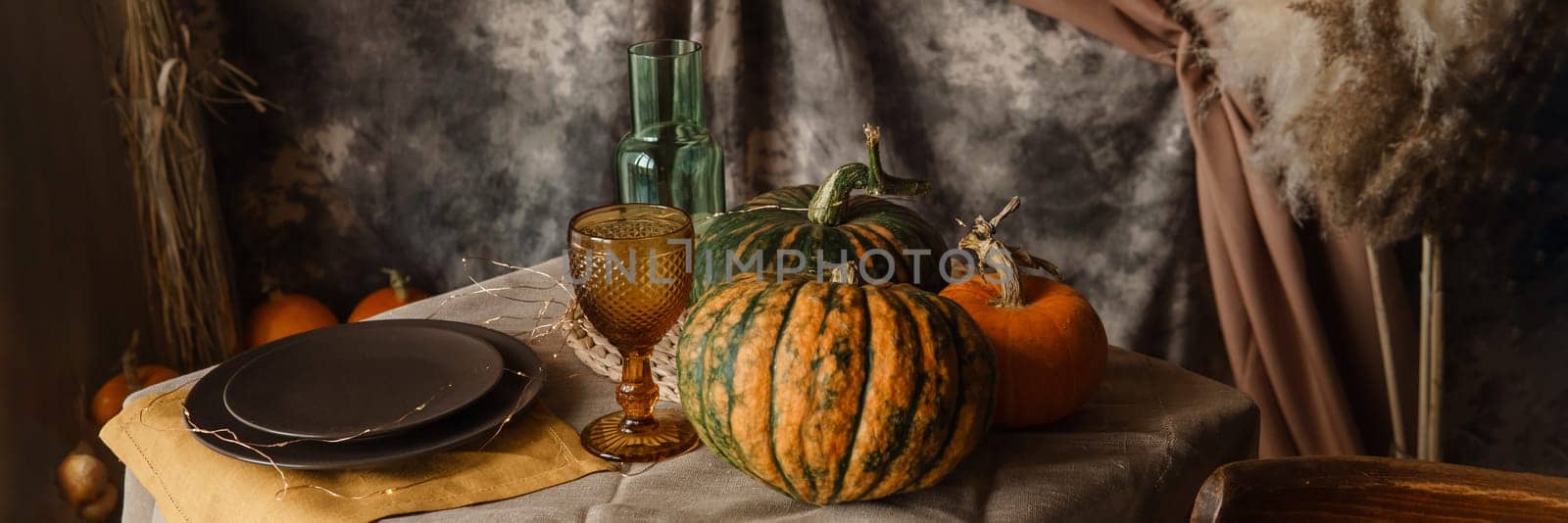 Autumn interior: a table covered with dishes, pumpkins, chair, casual arrangement of Japanese pampas grass. Interior in the photo Studio. by Annu1tochka