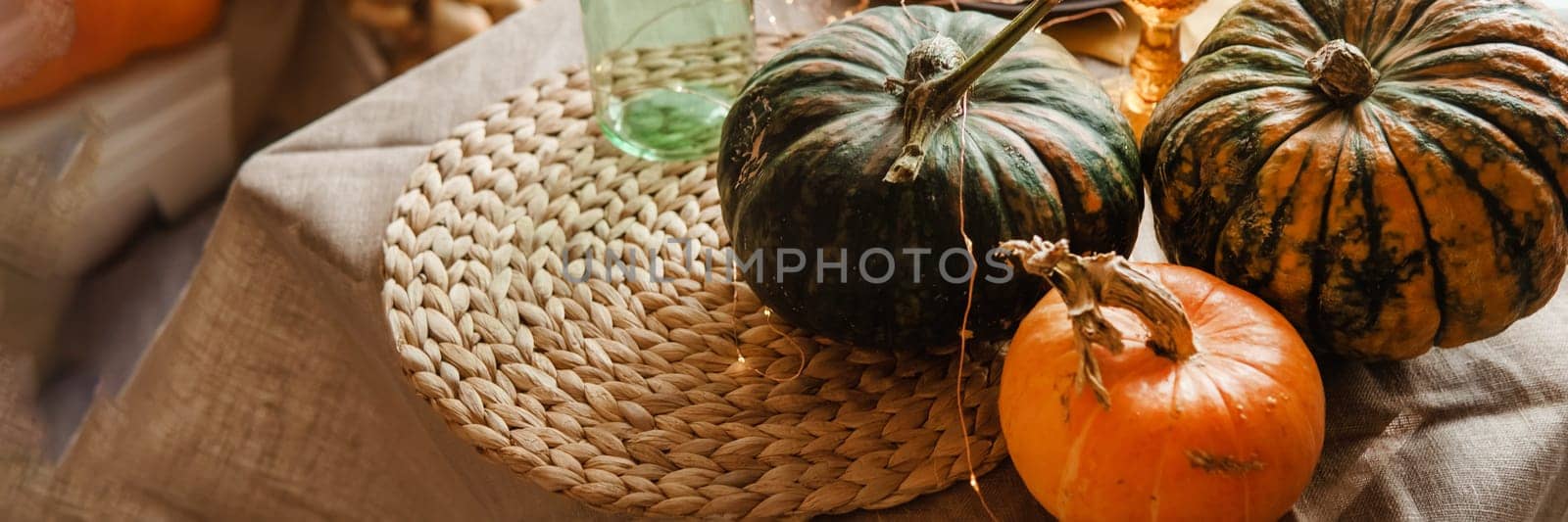 Autumn interior: a table covered with dishes, pumpkins, a relaxed composition of Japanese pampas grass. Interior in the photo Studio. Close - up of a decorated autumn table.