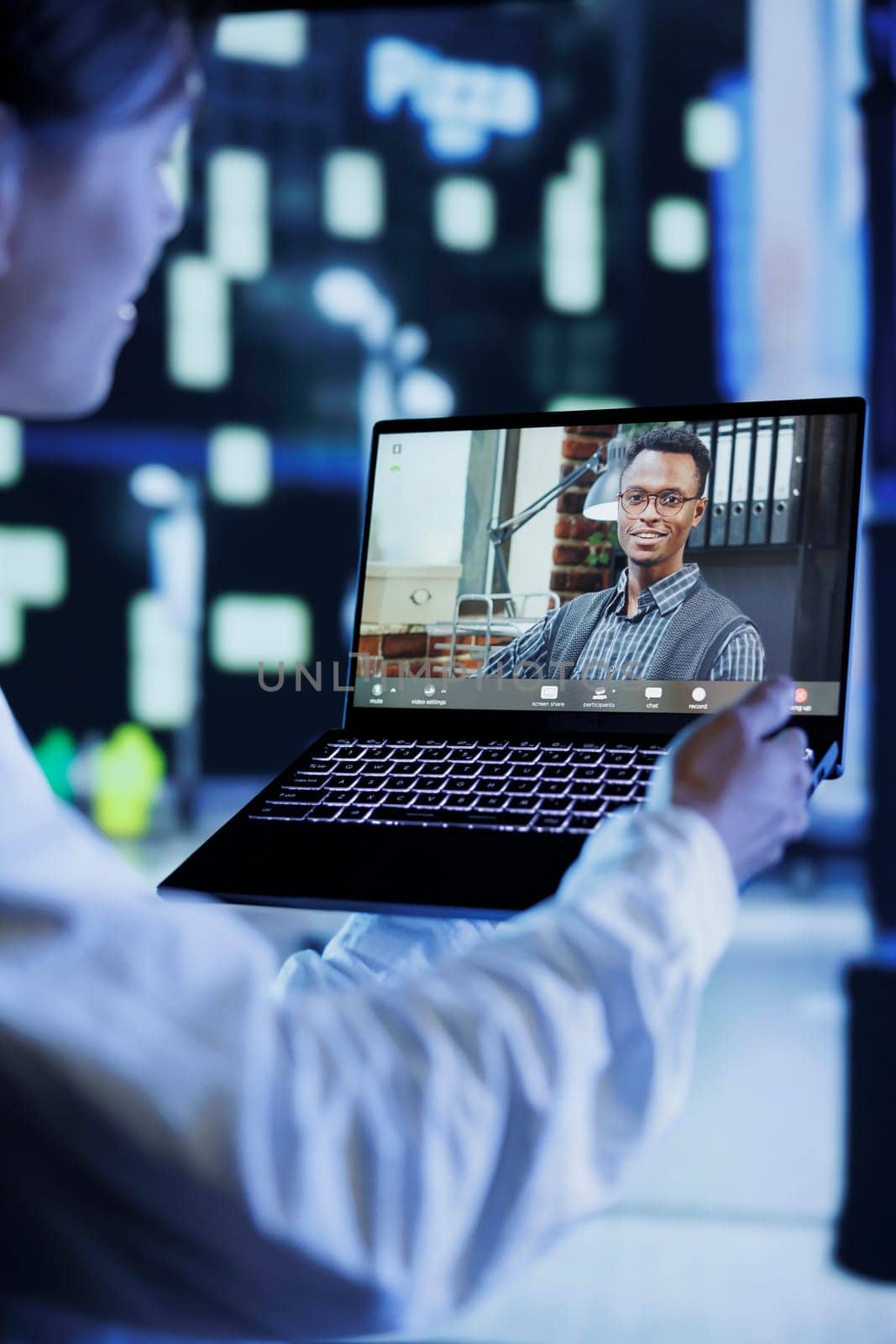 Close up of man in videocall with coworker while walking around city avenues at night, giving him work updates. Person uses laptop to show colleague nightlife cityscape in blurry background