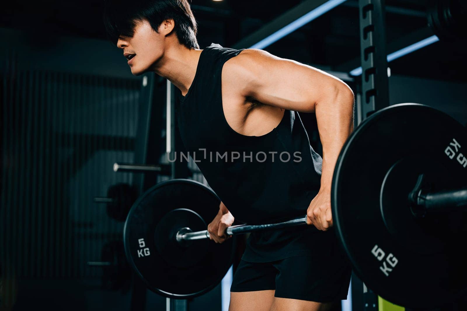 An Asian sportsman holding a barbell and lifting weights for a functional training and endurance workout that showcases his athletic body and determination. power lifting training concept