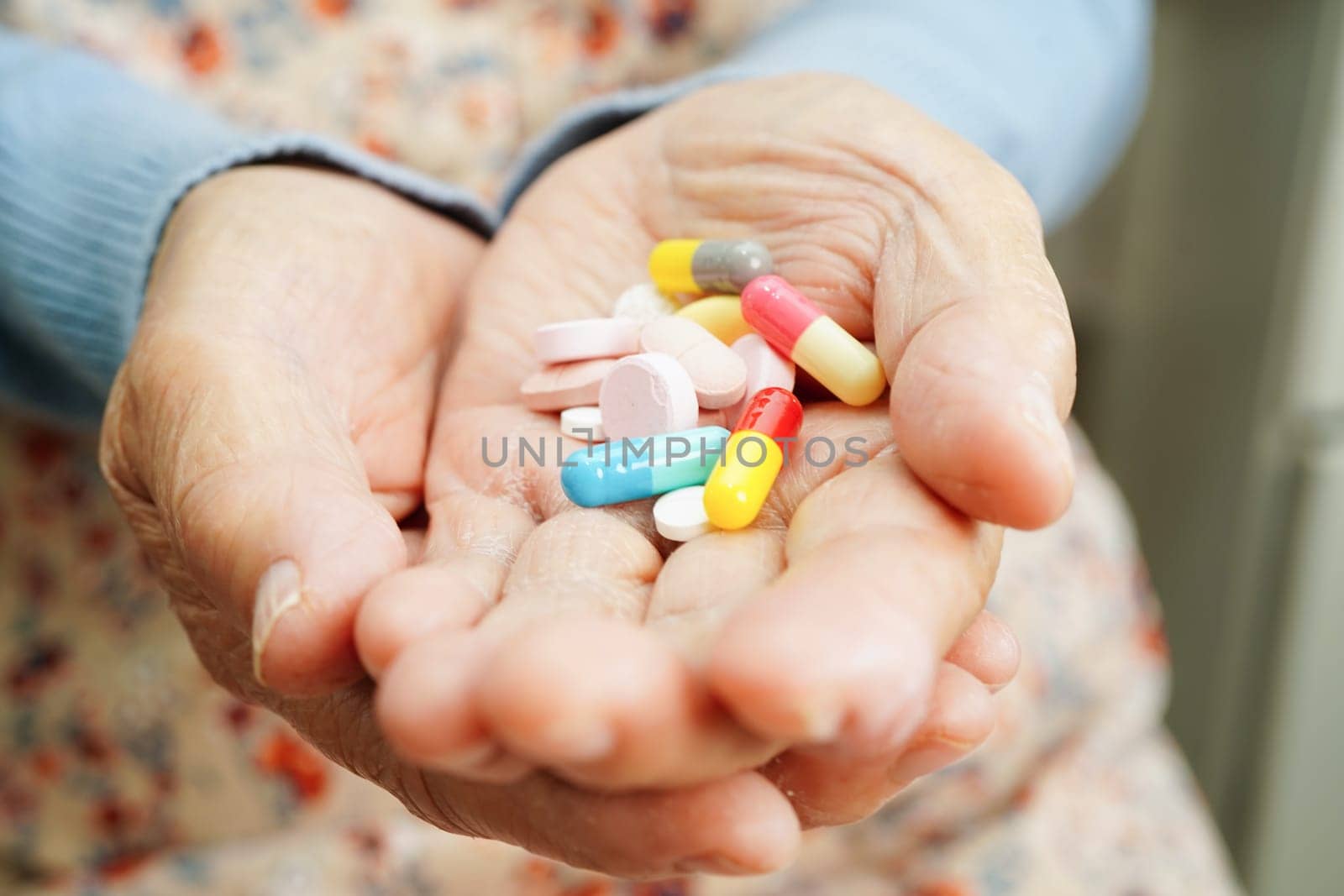 Asian elderly woman holding pill drug in hand, strong healthy medical concept. 