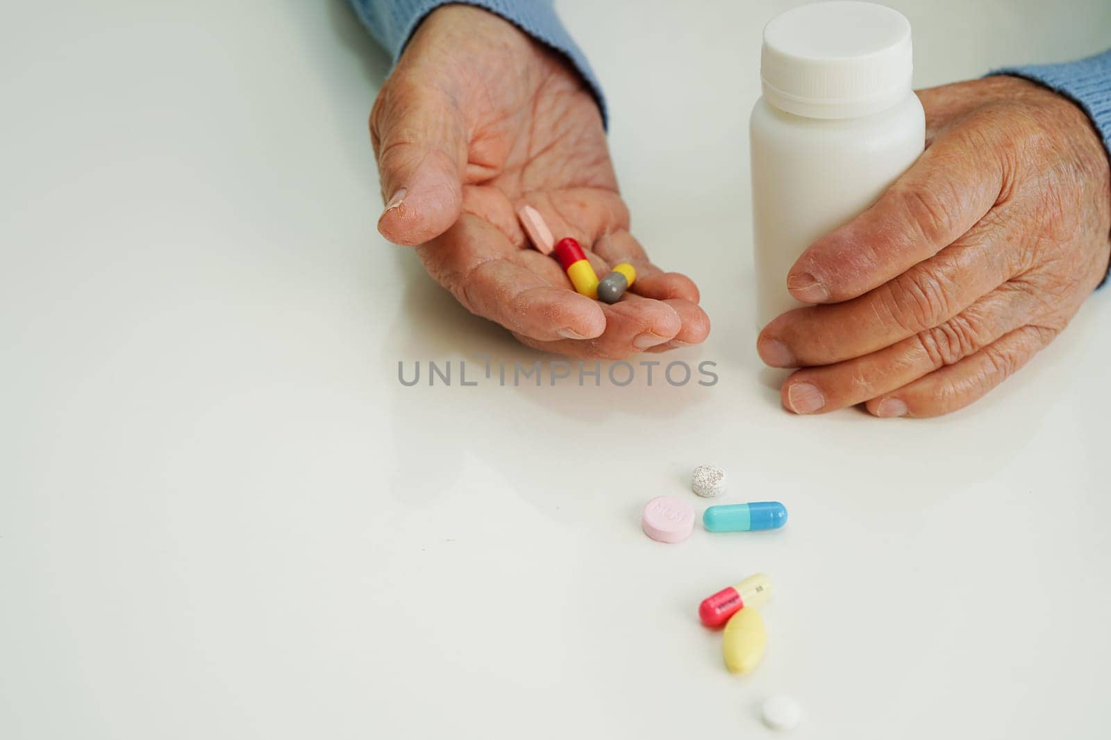 Asian elderly woman holding pill drug in hand, strong healthy medical concept. 