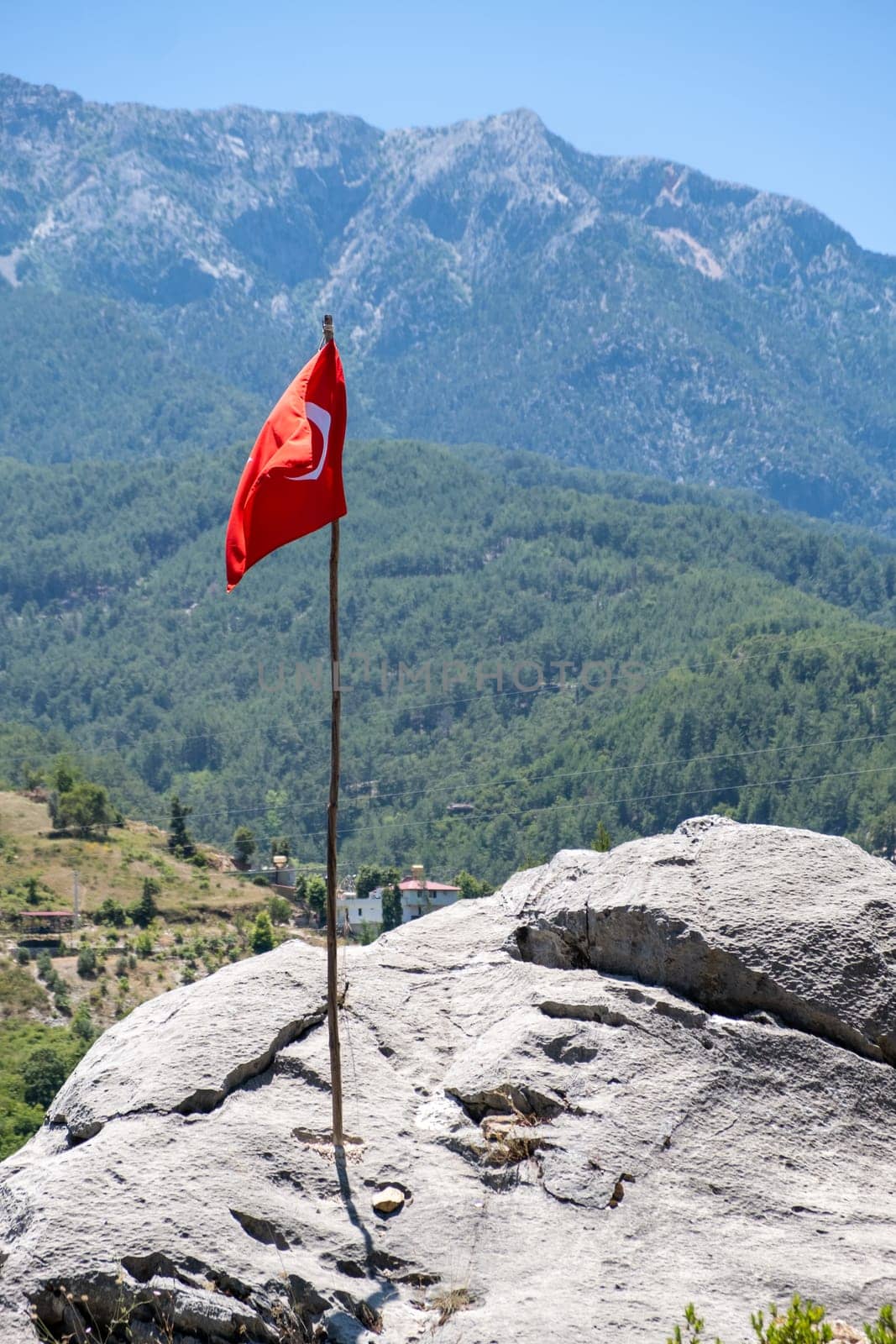 The Turkish flag is flying against the backdrop of beautiful mountains. The waving Turkish flag. The flag of Turkey on a flagpole with a copy space.