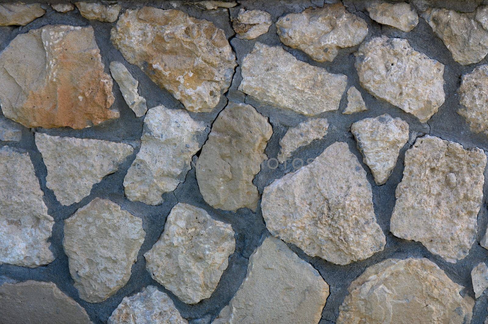 Rugged stones form an intriguing wall, blending earthy shades and natural shapes under warm sunlight.