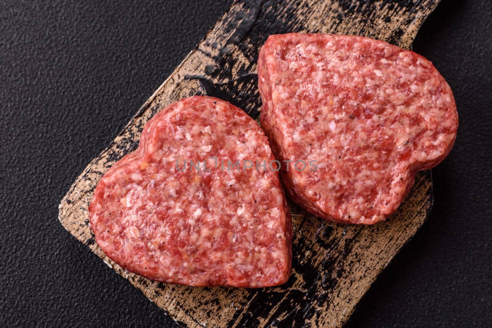 Raw beef or pork burger patty in the shape of a heart with salt, spices and herbs