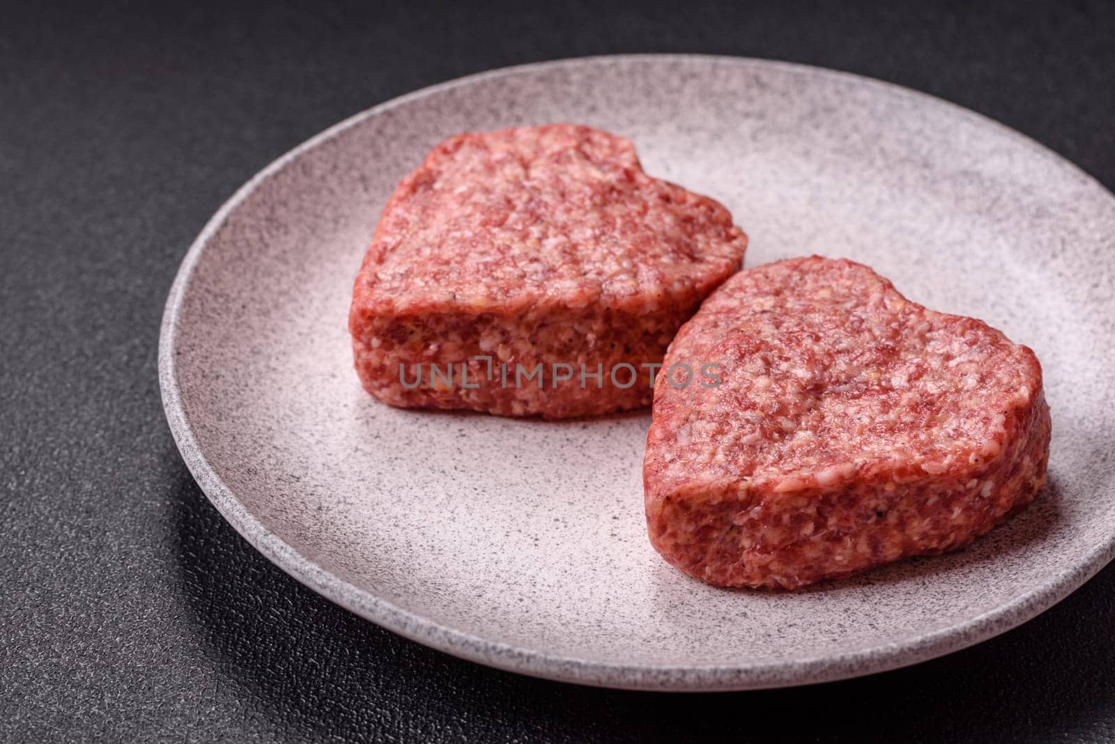 Raw beef or pork burger patty in the shape of a heart with salt, spices and herbs