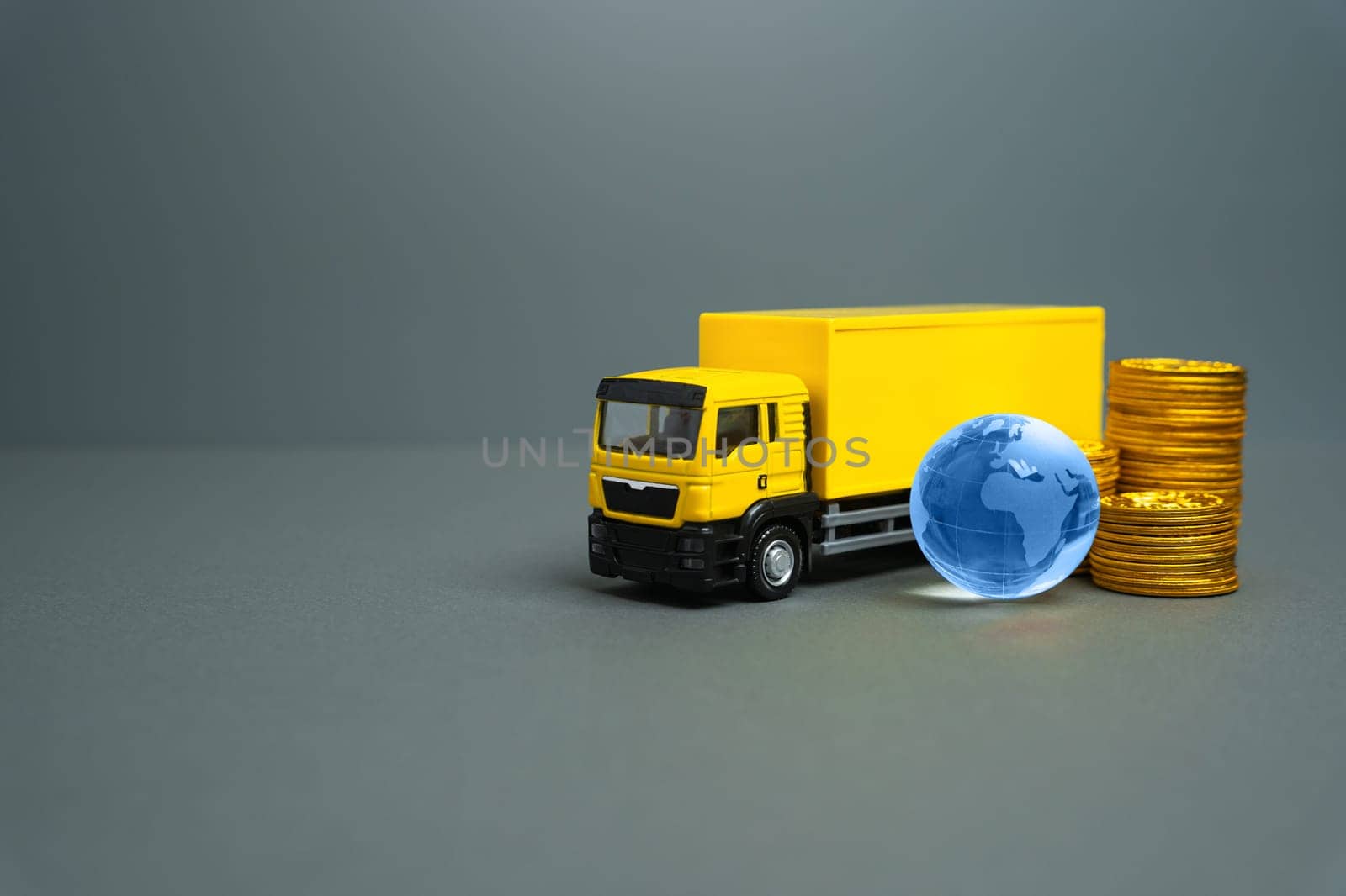 Yellow truck with globe and money coins. International transportation of goods and cargo. Transport logistics companies. Economic relations. Trade.