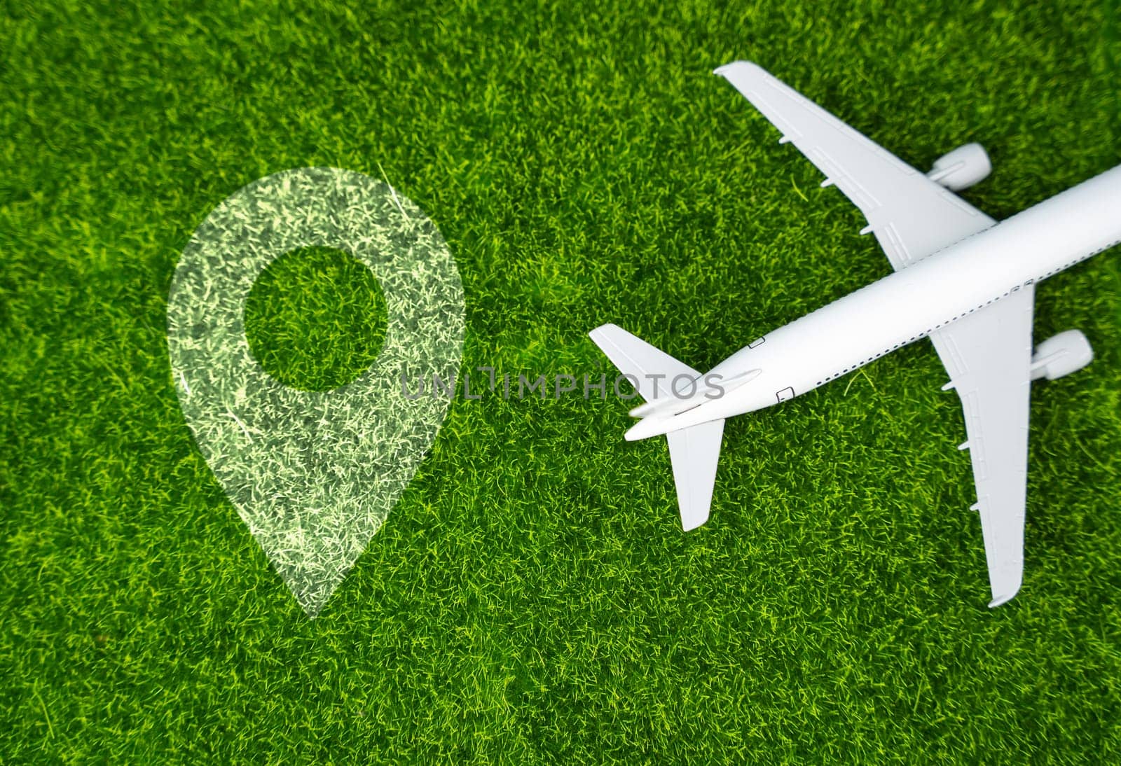 Airplane and geolocation sign on the grass. Travel and business trips. Transport system and infrastructure. Air communication. World flight routes.