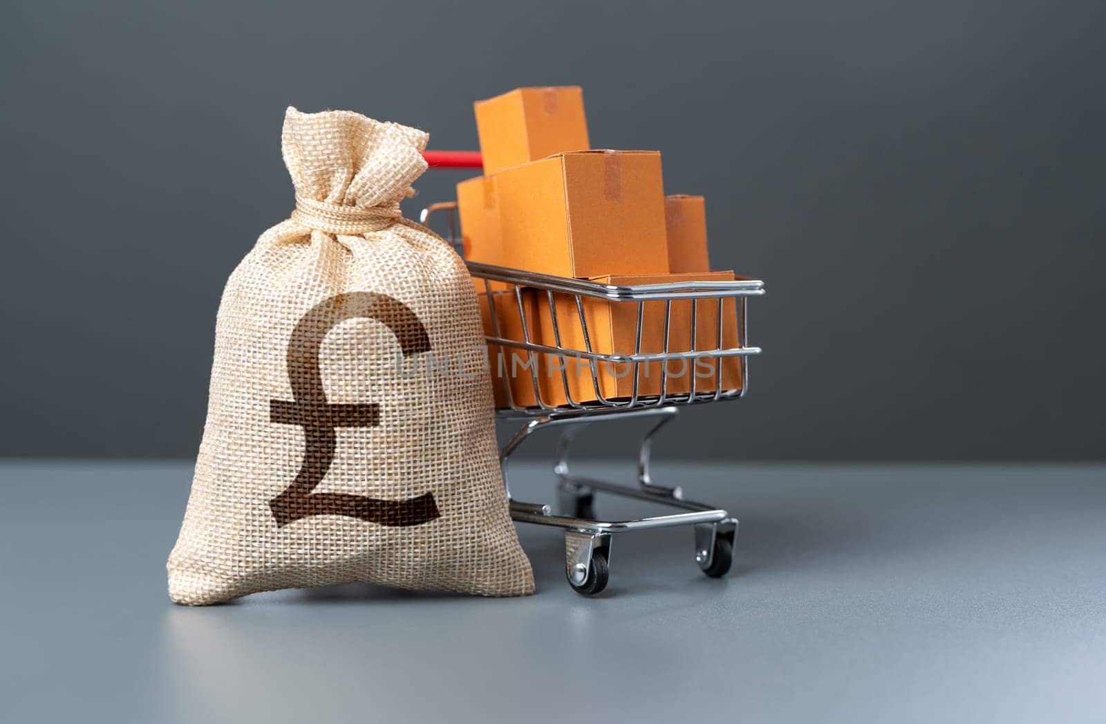 Shopping cart with boxes of goods and british pound sterling money bag. Profit from the sale of goods. Marketing and market research. Purchasing power of buyers. Start-up equipment purchase.