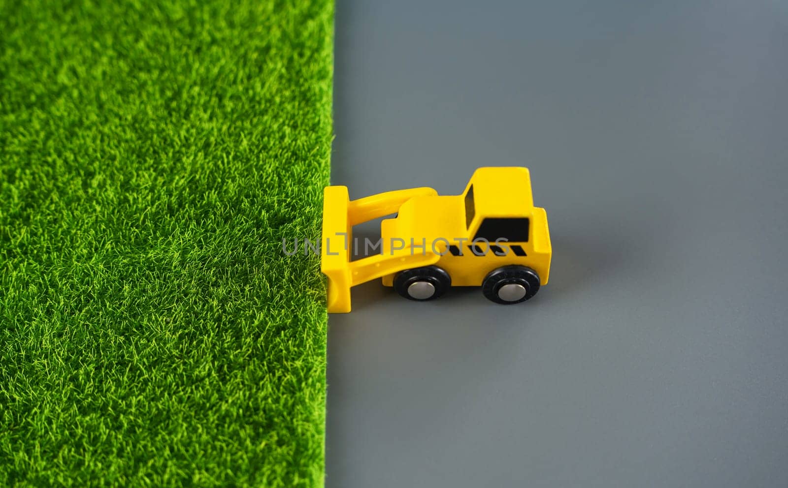 The bulldozer removes the grass and leaves the concrete. The concept of destruction of nature for technogenic development. Expanding cities space . Urbanization, increasing influence on environment.