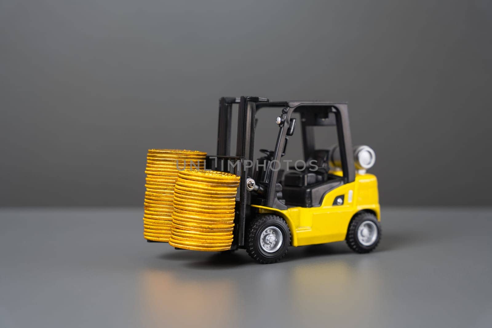 Forklift and stacks of coins. Increase income in export of goods. Trade traffic increasing. Production rise. Growing transportation prices. Growth in profits. High shipping rates.