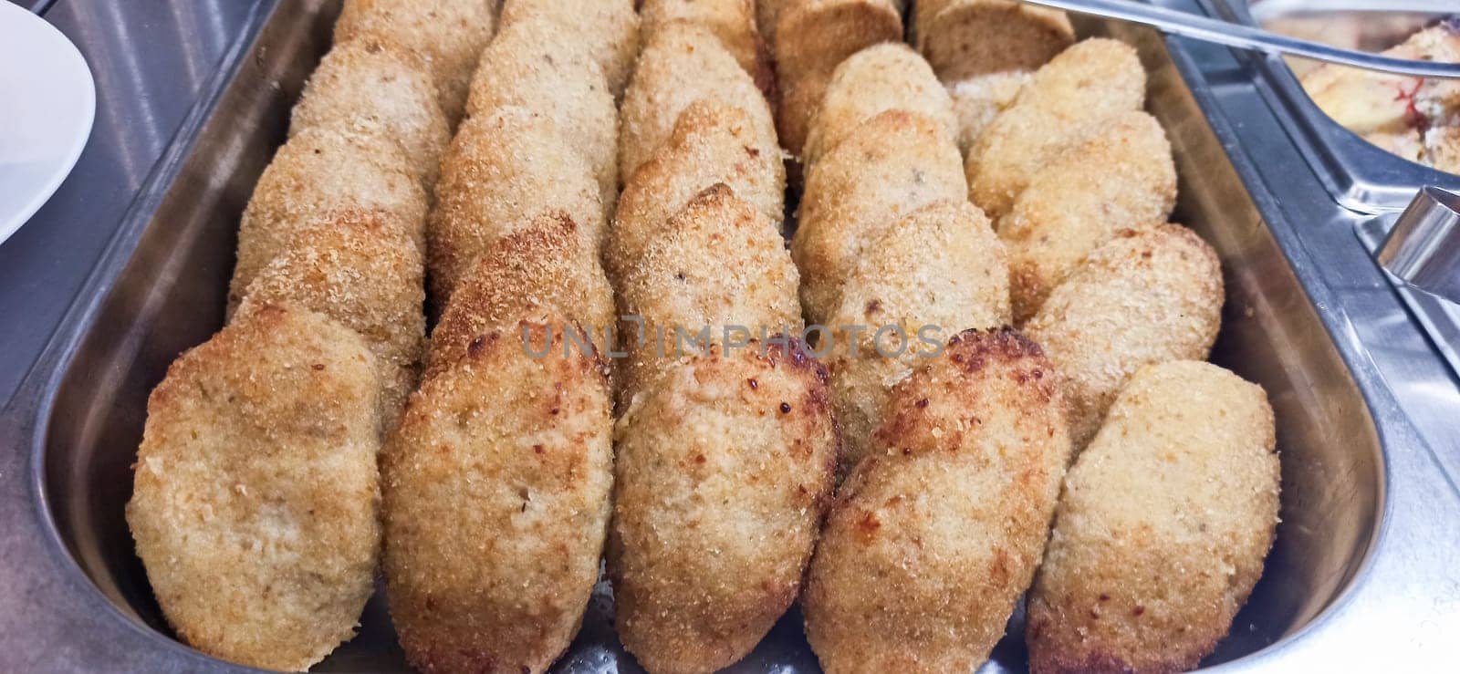 Delicious, golden-brown fried dumplings line a metal tray, showcasing their crispy texture and inviting appearance. These treats are perfect for sharing at any festive gathering.