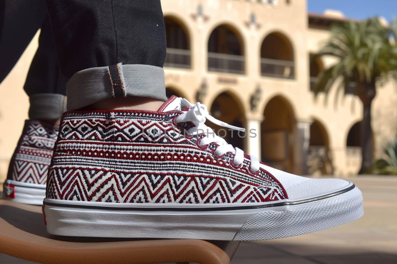 Casual fashion scene of a young person sitting, highlighting artistic sneakers with textured patterns.