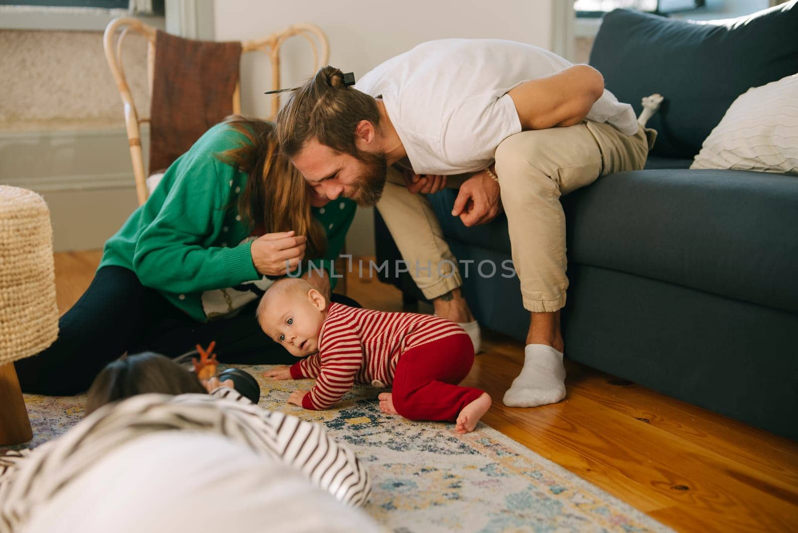 A joyful family is happily playing with their baby on the cozy living room floor filled with warmth and love