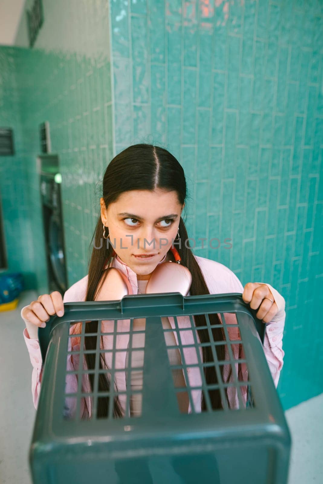 A young girl joyfully poses with a laundry basket in a vibrant and colorful bathroom setting filled with personality