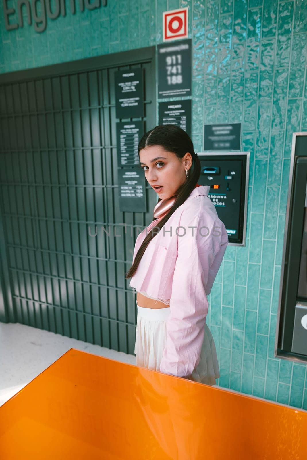 A confident woman poses gracefully in a vibrant urban setting, showcasing the latest contemporary fashion