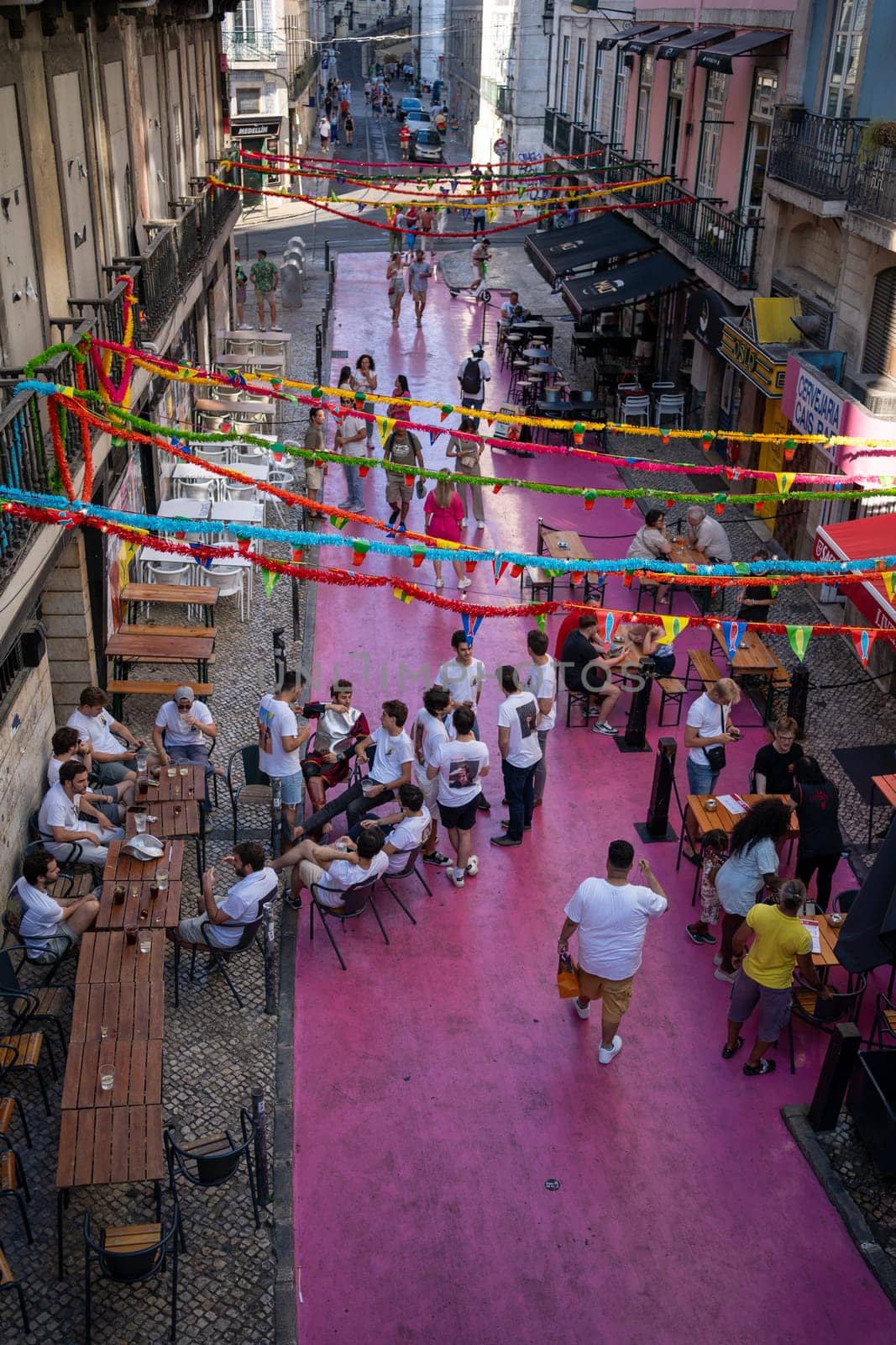 Crowd of people gathered at lively gay pride parade on famous Pink Street in Lisbon, under colorful decorations and festive atmosphere, celebrating diversity and inclusion