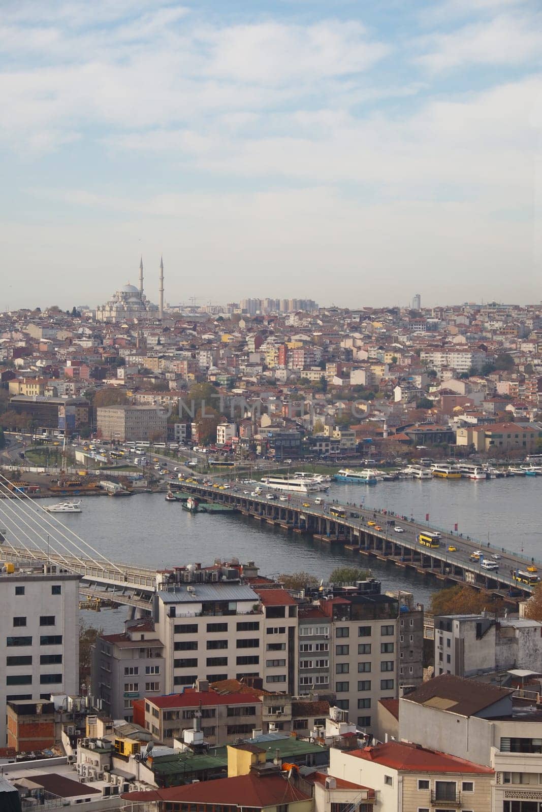 A stunning view of Istanbul's skyline showcases the Golden Horn, Galata Bridge, and vibrant neighborhoods under a bright blue sky. Boats and buildings fill the bustling waterfront area.