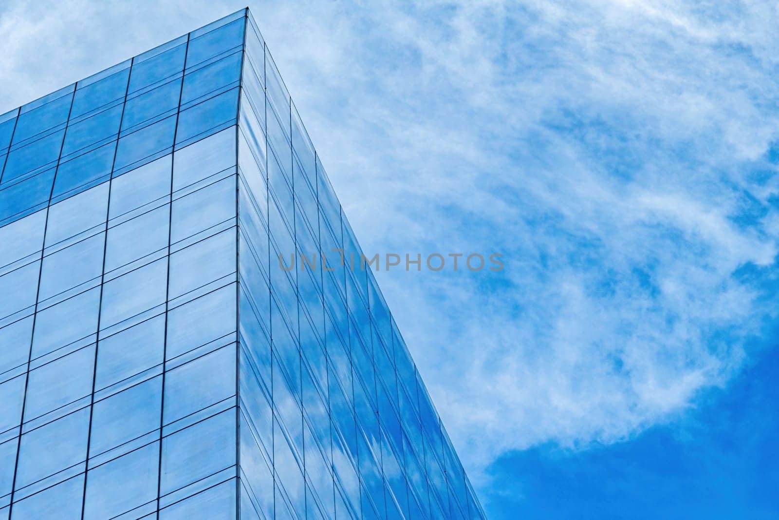 Modern glass building top detail, background for business corporate, building against blue sky reflection.