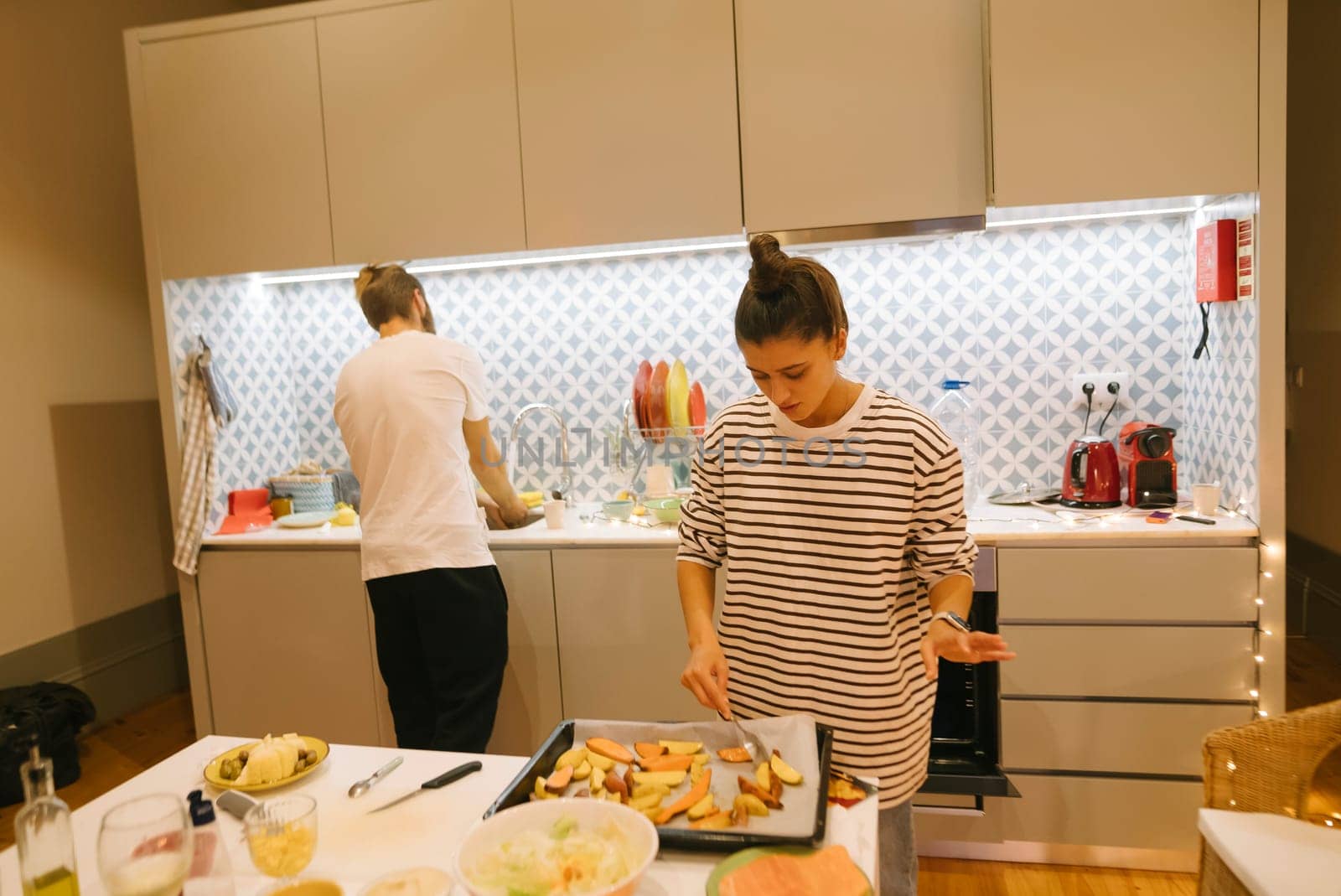 A couple happily enjoys cooking delicious meals together in a stylish kitchen, showcasing teamwork and creativity