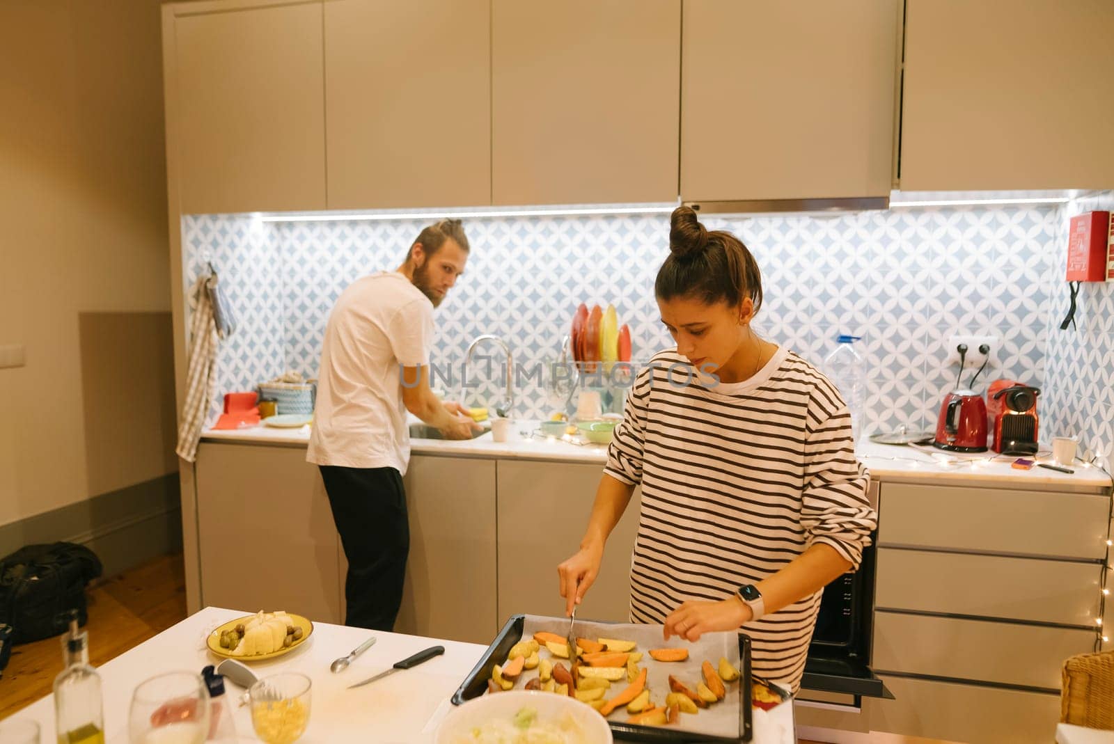A couple joyfully prepares a meal together in their modern kitchen, showcasing teamwork and enhancing their bond