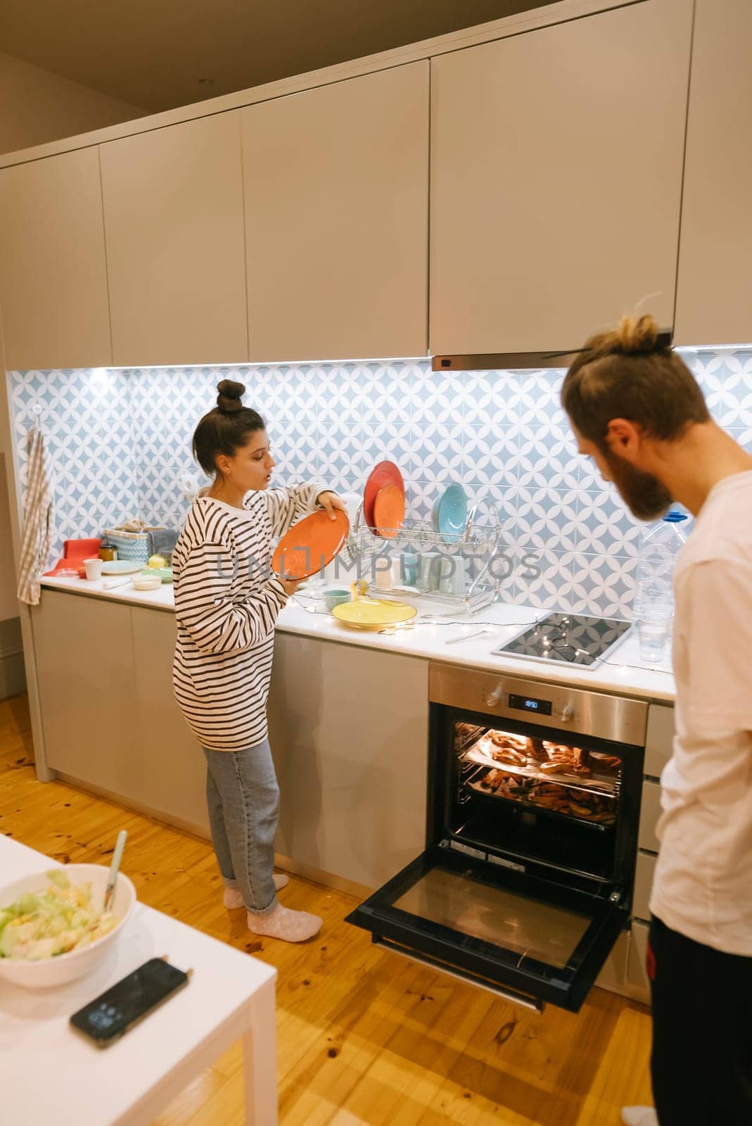 A couple joyfully preparing food together in a stylish, modern kitchen, highlighting their teamwork and culinary skills