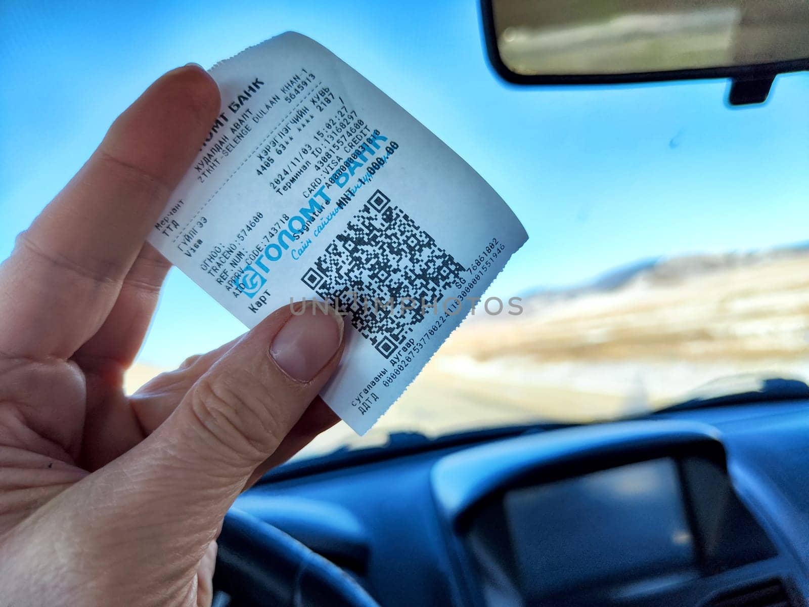 Ulaanbaatar, Mongolia - November 03, 2024: A traveler holds a gasoline receipt while driving through Mongolia, documenting the journey near Ulaanbaatar.
