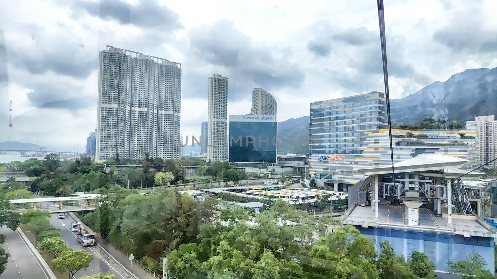 Hong Kong, China - April 08, 2024 - Modern skyscrapers rise above greenery and streets, reflecting the vibrant city life in Hong Kong during an overcast afternoon.