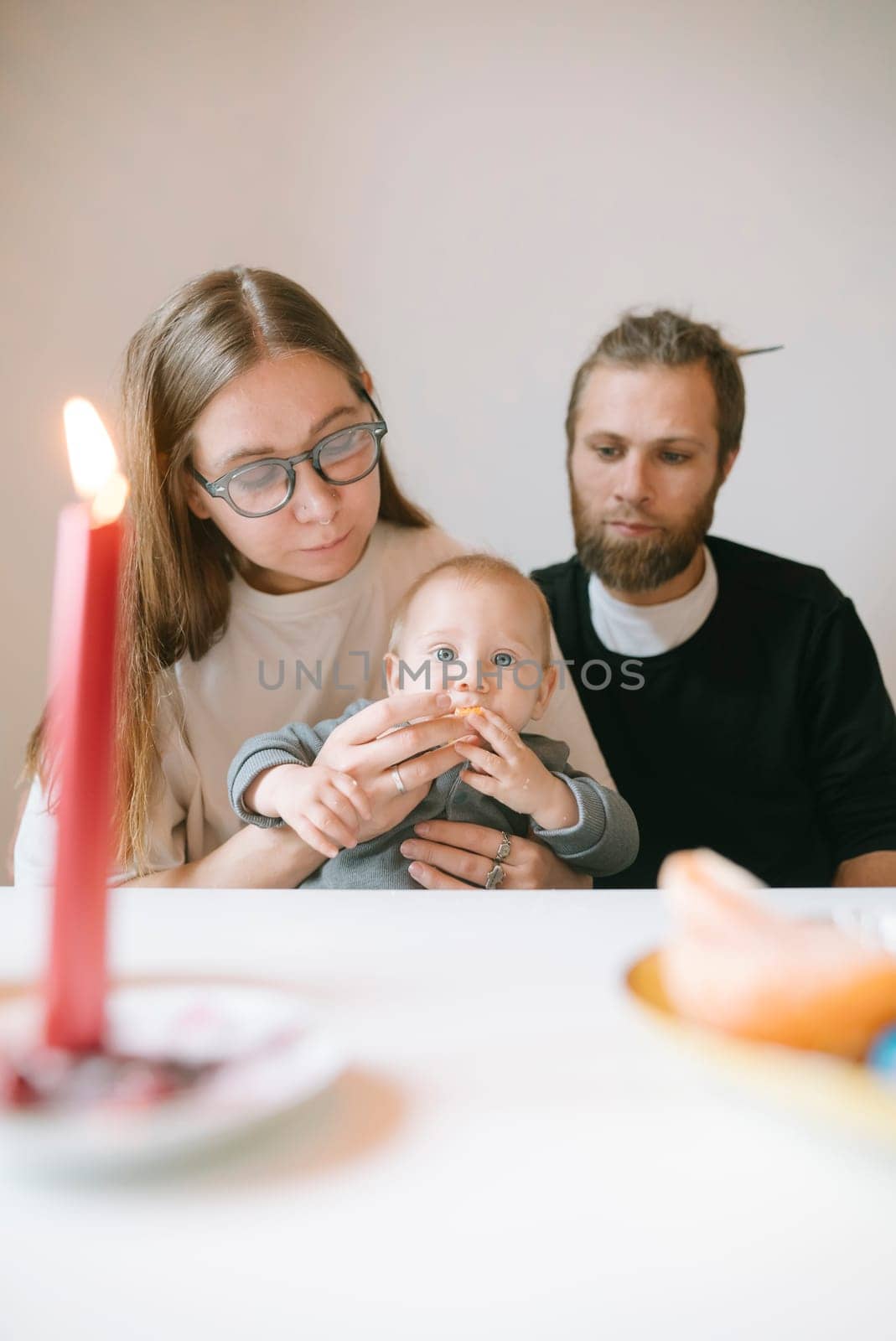 A loving family shares a warm moment with their baby, enjoying a cozy candlelit dinner and creating memories