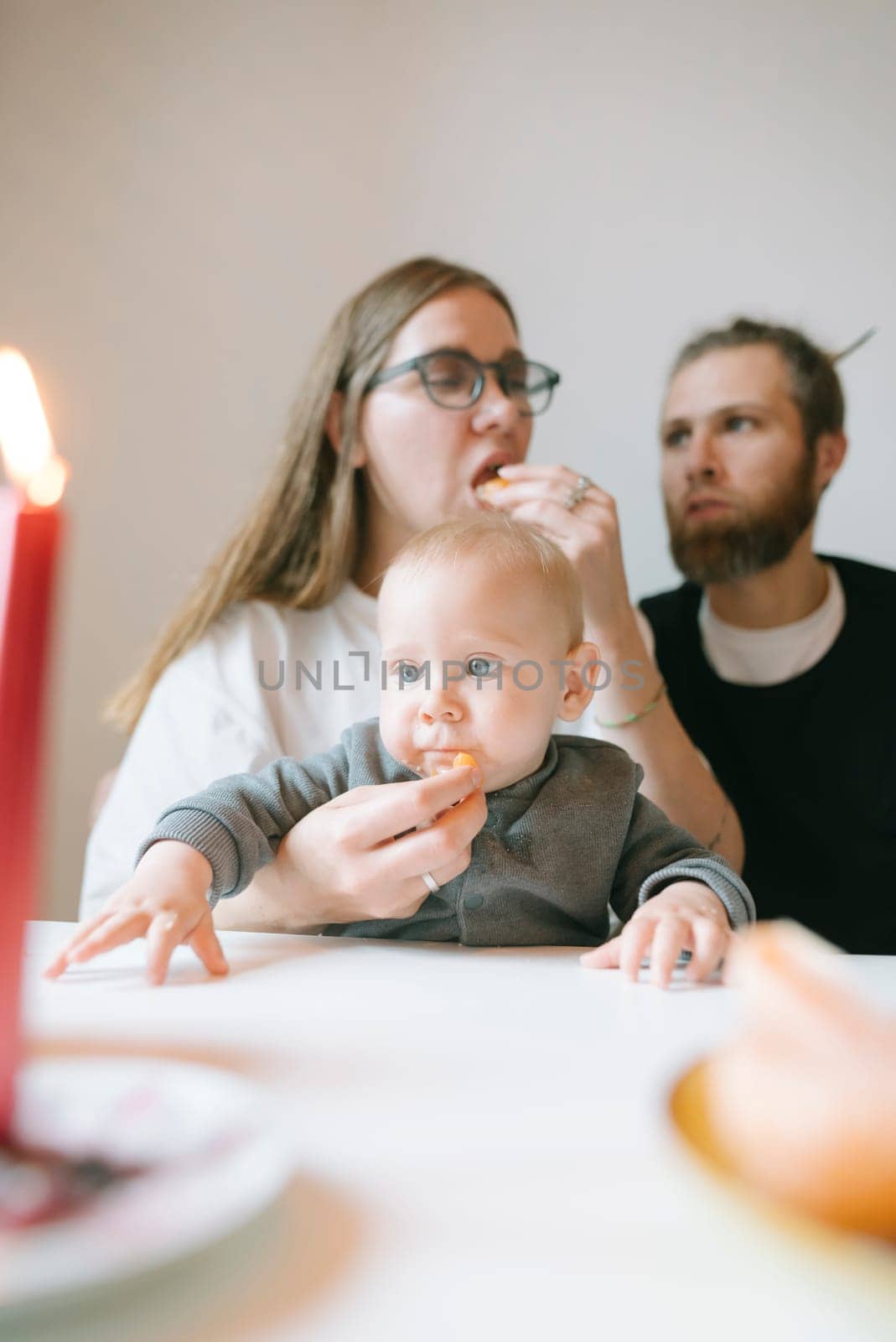 A cozy family dinner features a cute baby joyfully savoring a meal in a delightful candlelight ambiance