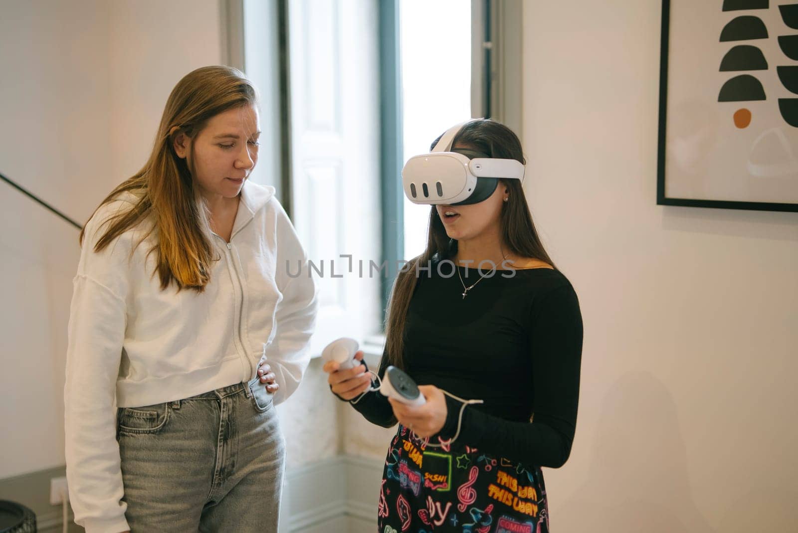 Two young women are actively engaging and having fun with a virtual reality headset in a sleek, modern setting