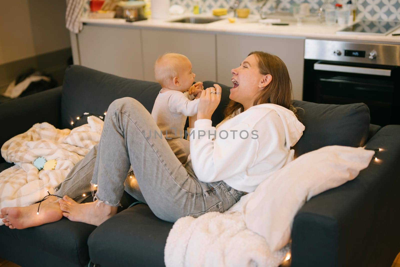 In a delightful and joyful interaction, a mother is engaging with her baby in a warm and cozy home setting
