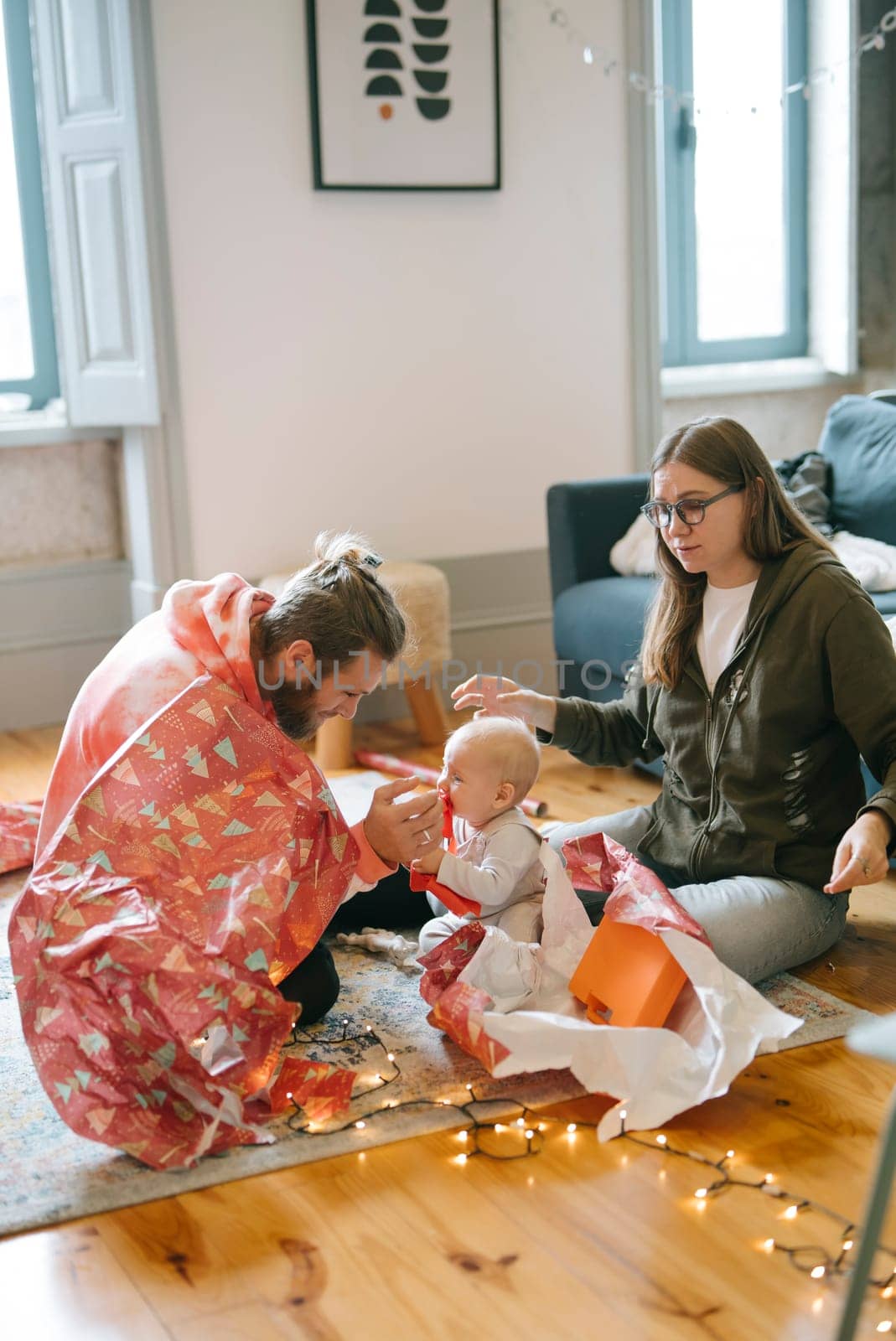 A joyful family is delightfully enjoying a precious moment with their adorable baby, surrounded by festive decorations