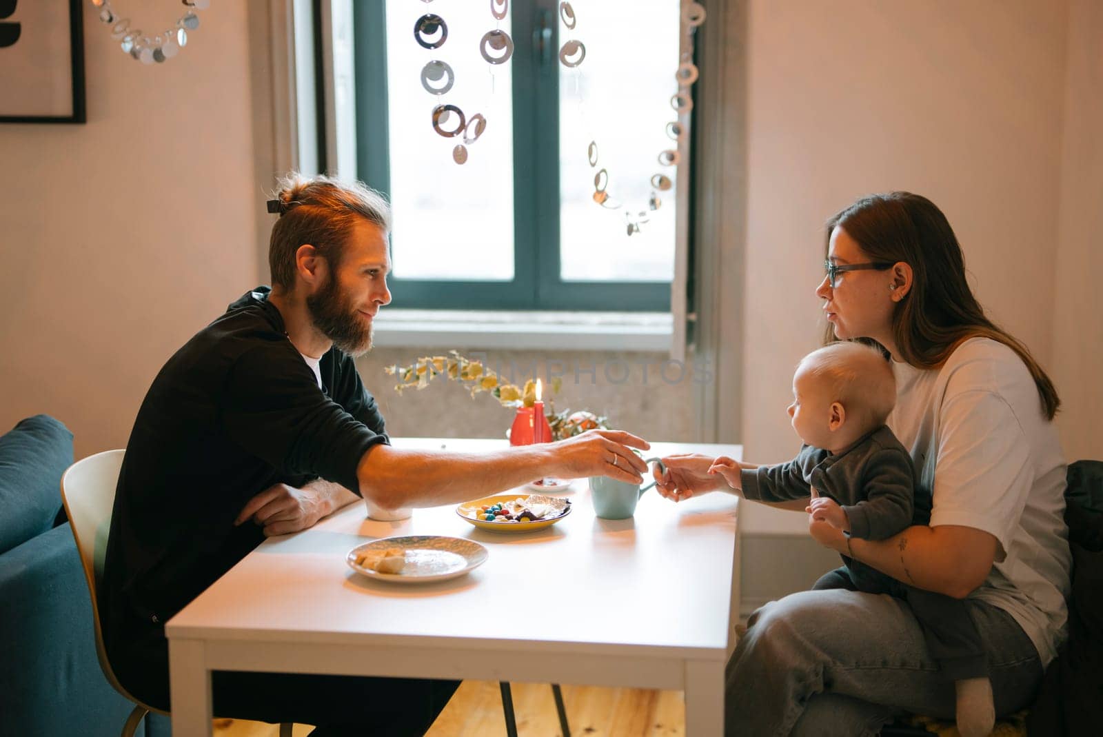 A heartwarming family breakfast scene takes place at home featuring a couple lovingly caring for their baby