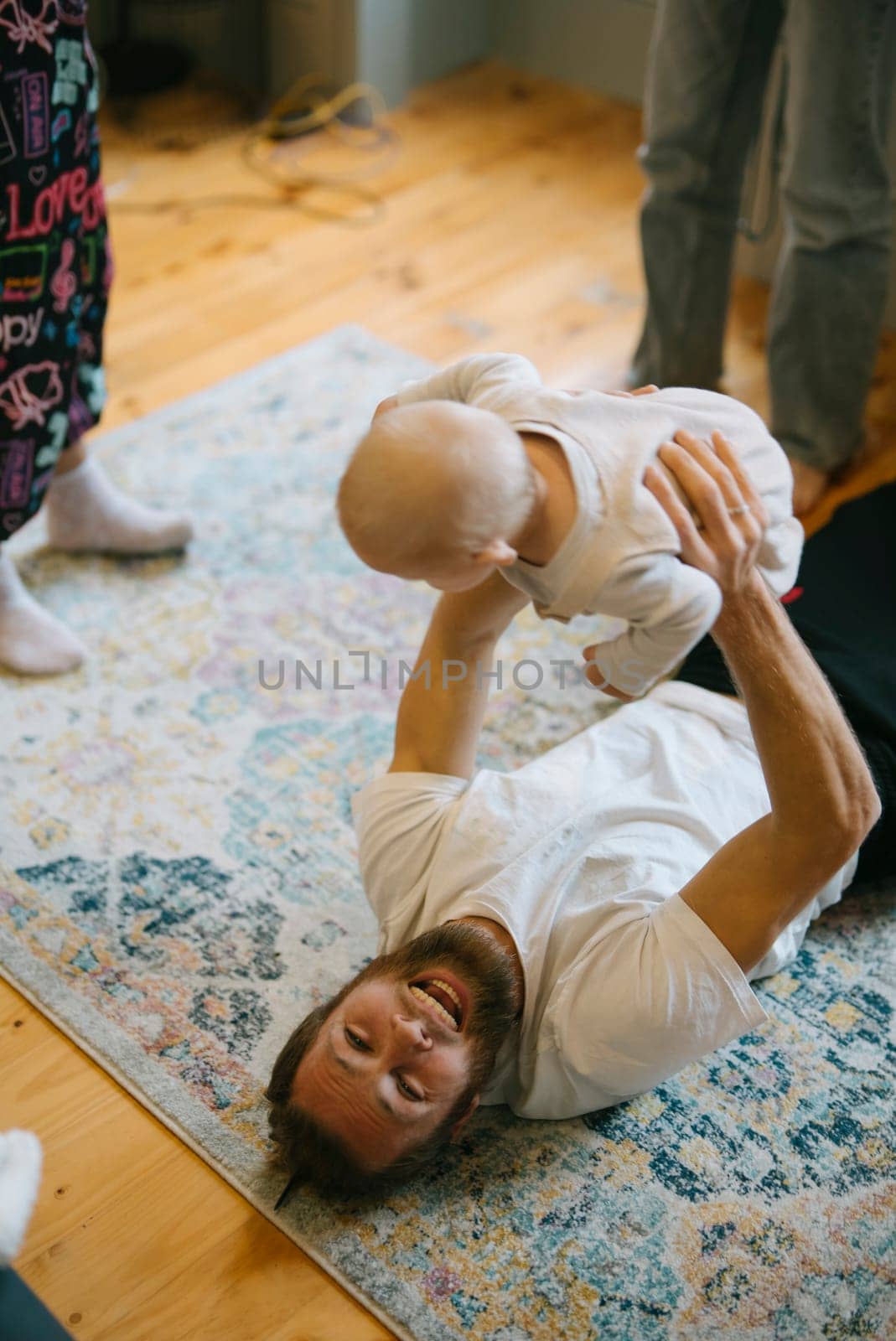 A father joyfully plays with his baby on the soft floor, celebrating love and cherished family bonds