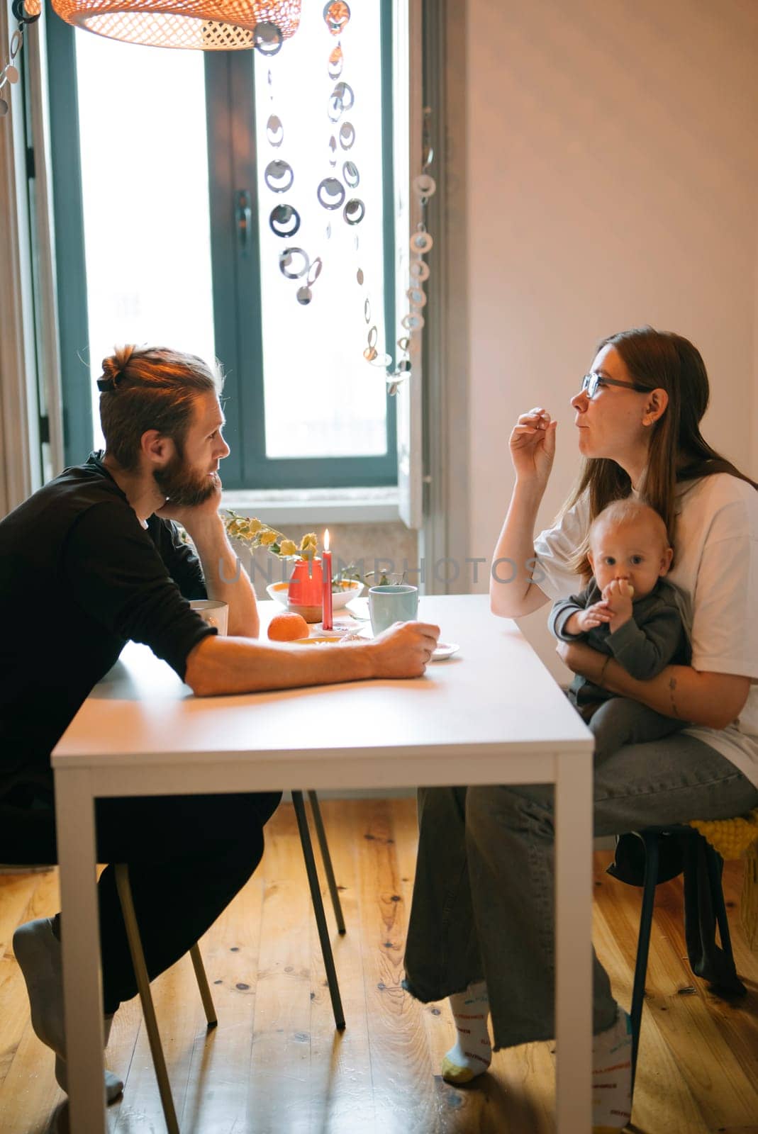 Parents have a heartfelt conversation with their baby at home, beautifully captured in a cozy setting