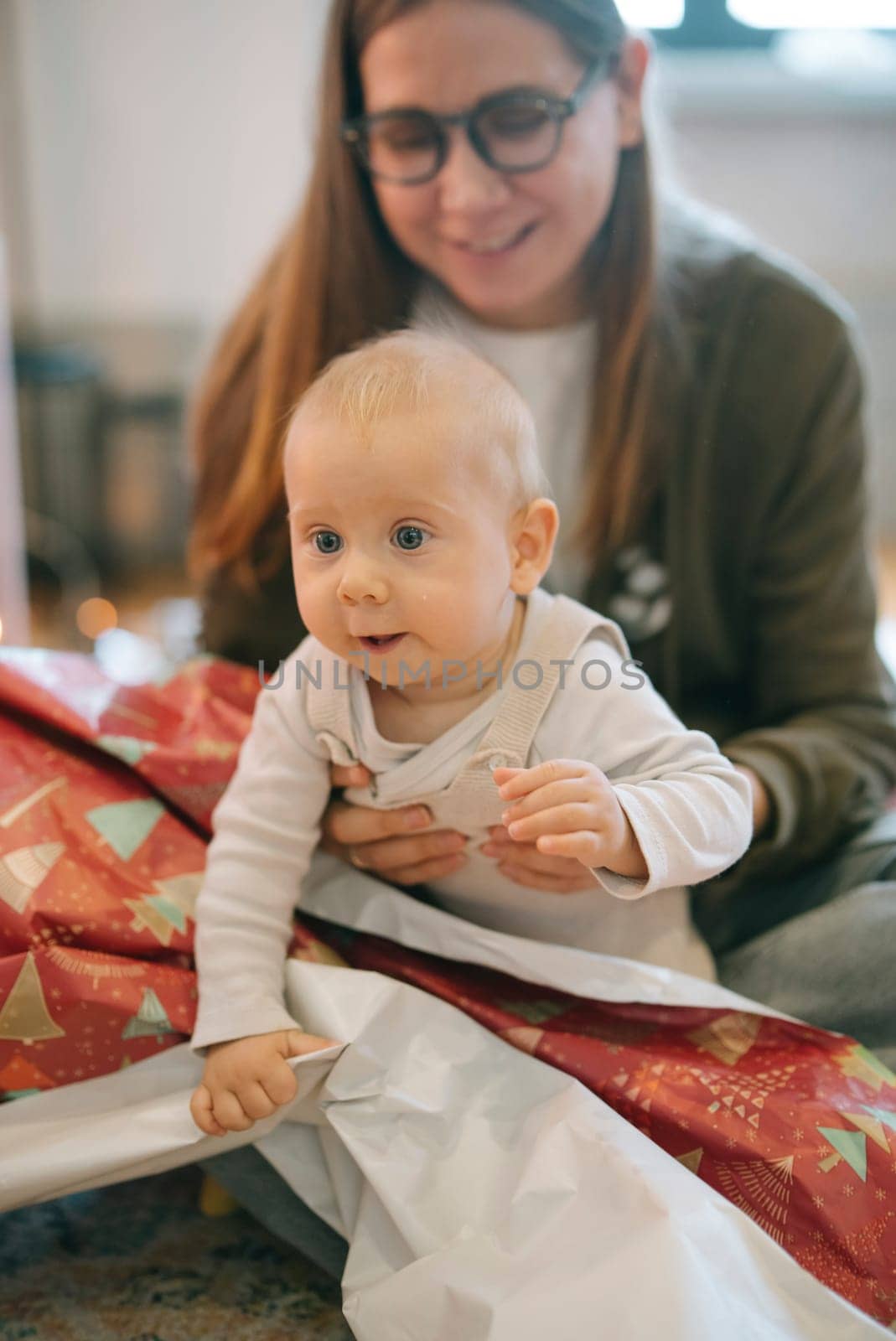 A heartwarming scene of a baby and parent joyfully sharing moments while unwrapping presents together