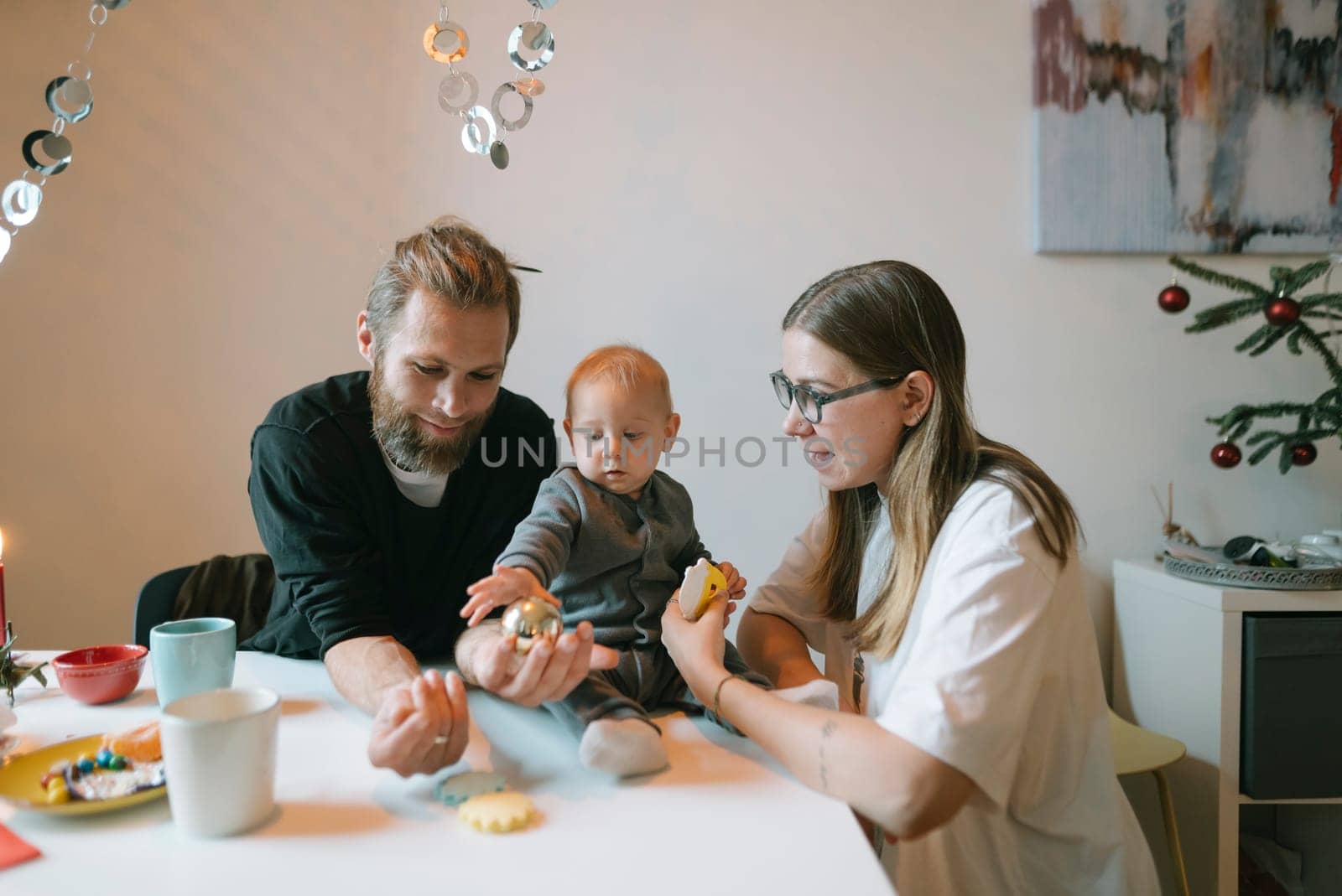 A loving family joyfully gathers together in their cozy kitchen to bake colorful cookies during the festive season