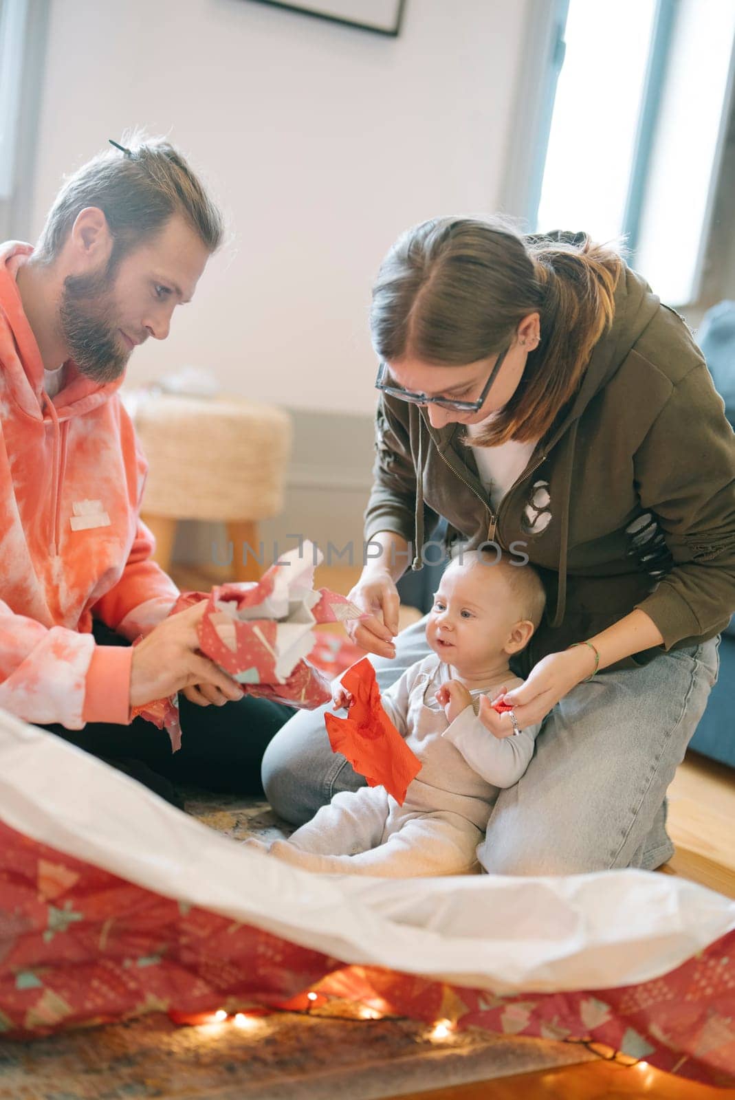A heartwarming scene where a loving family joyfully celebrates while unwrapping thoughtful gifts with their baby