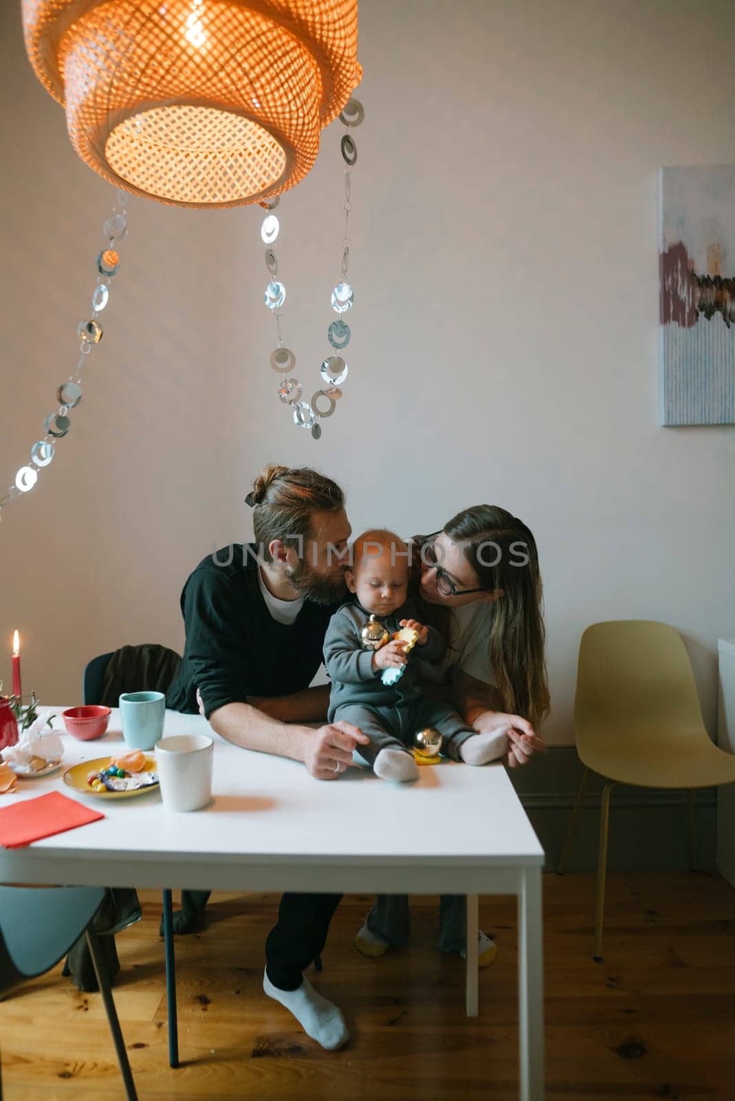 In a tender and heartwarming moment, a loving couple shares beautiful affection with their baby at home