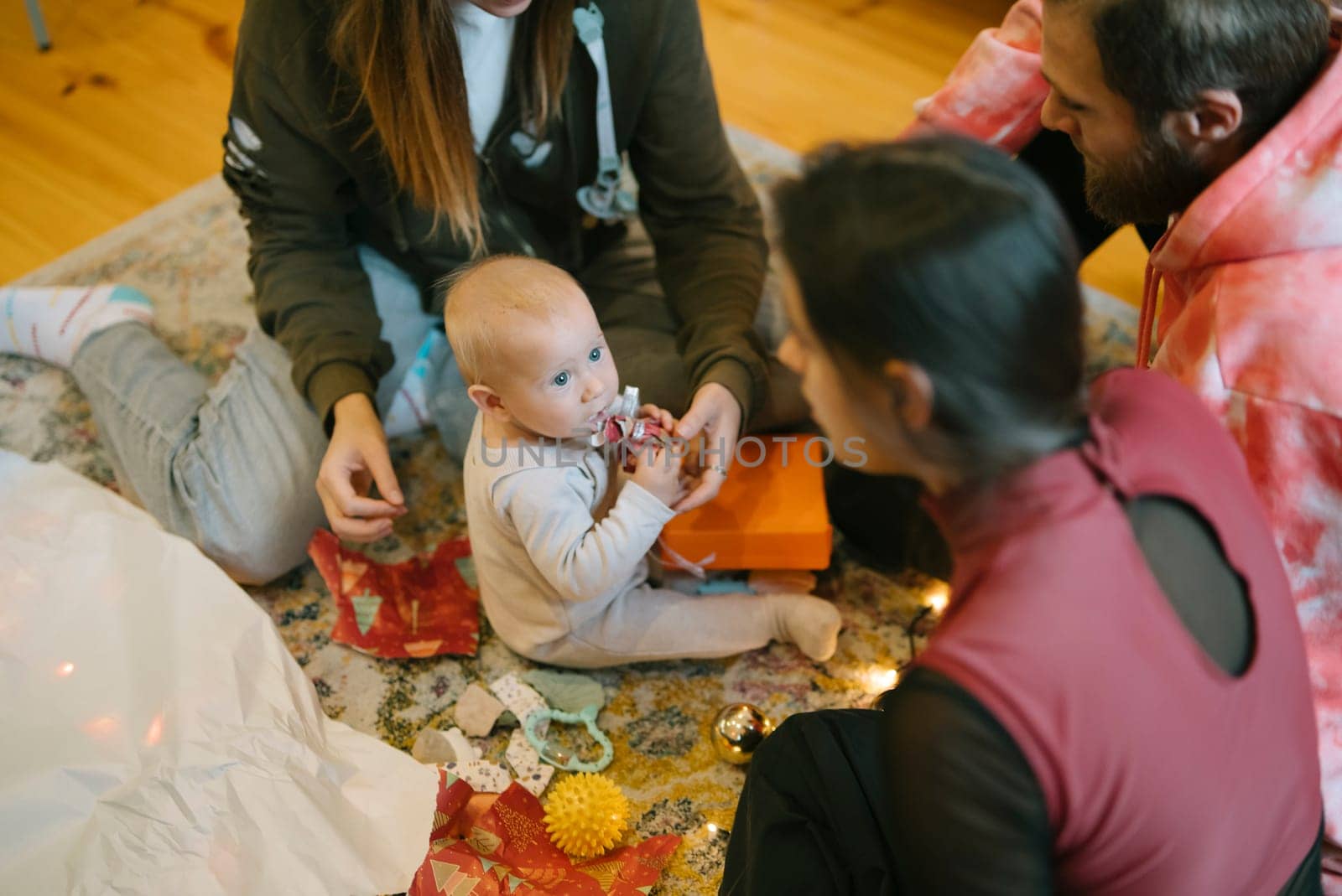 A cozy family moment featuring a joyful baby surrounded by their loving family members and festive decor