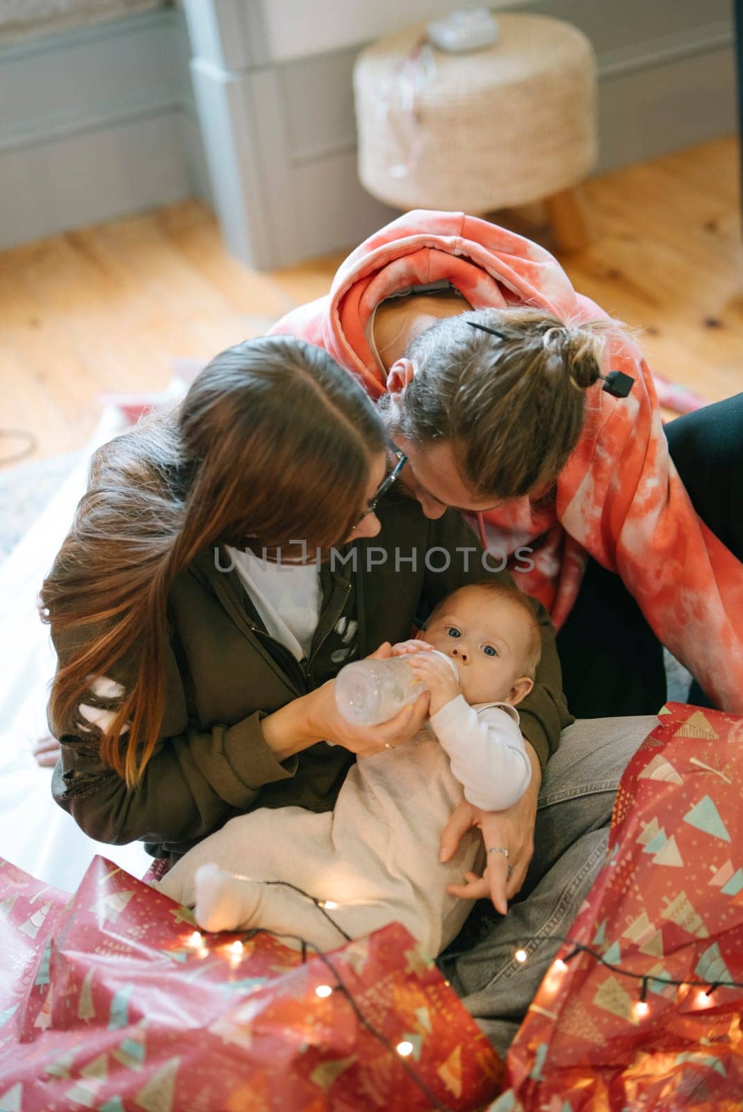 This holiday scene captures a baby joyfully enjoying family time amid delightful festive decorations