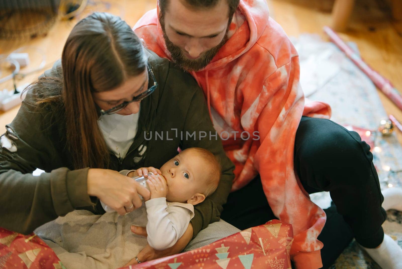 A precious family moment where parents lovingly care for their adorable baby amidst a cozy and joyful holiday setting