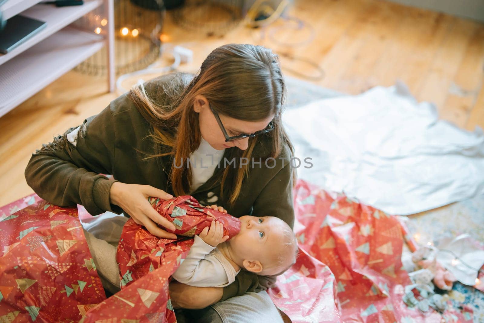 A loving parent shares a precious gift unwrapping moment filled with joy and happiness together with their little baby