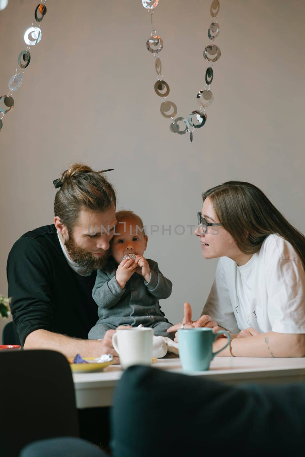 A loving couple joyfully shares a beautiful moment with their adorable baby in a cozy, warm cafe ambiance